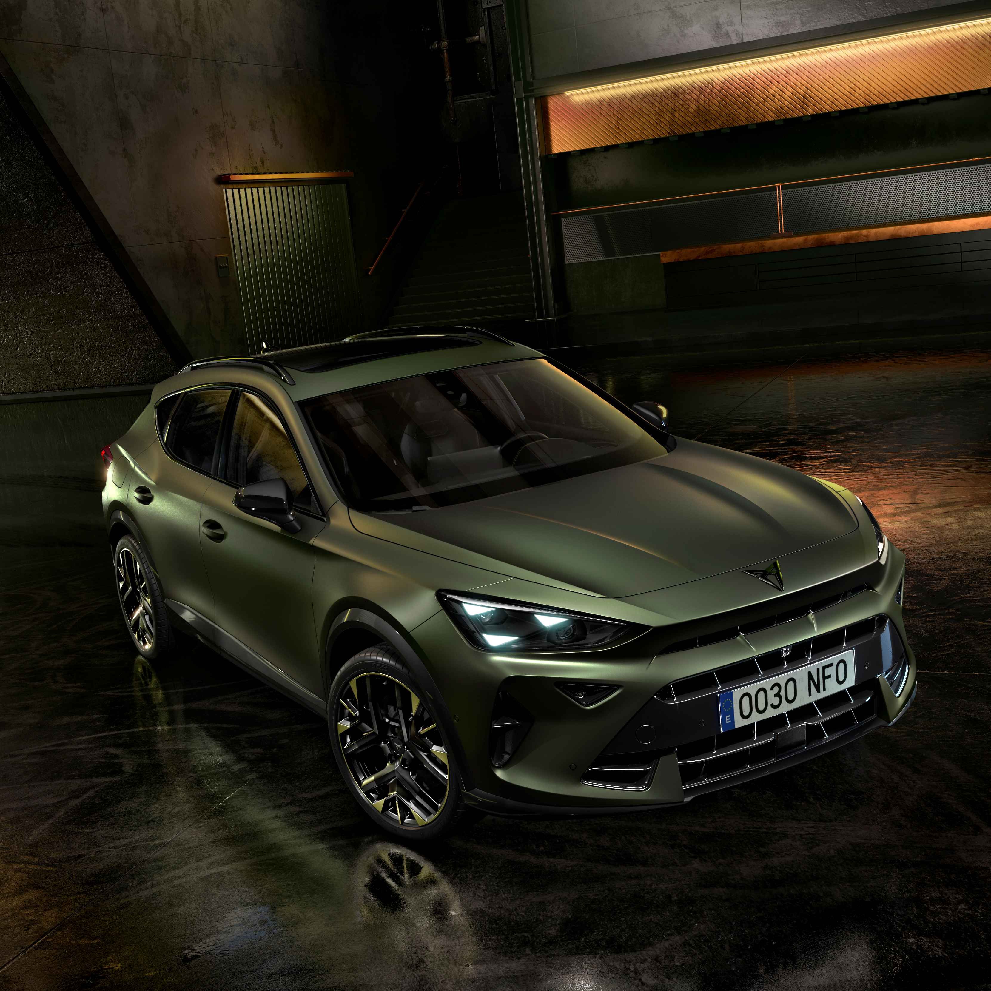 Model CUPRA v zelenej metalíze stojí v čiernom interiéri s moderným osvetlením na stenách.