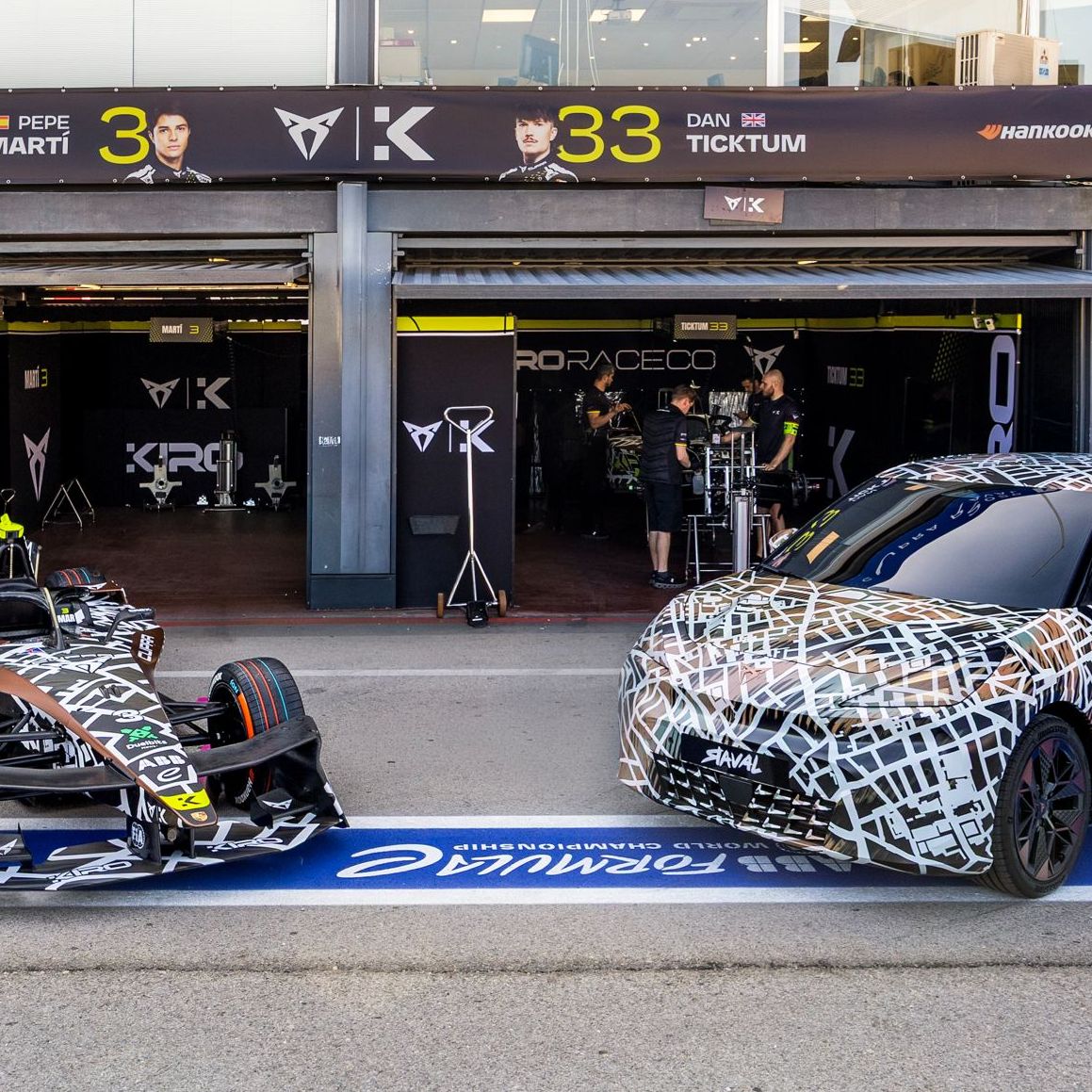 CUPRA Raval a Formula E zaparkované pred tímovými boxami. 