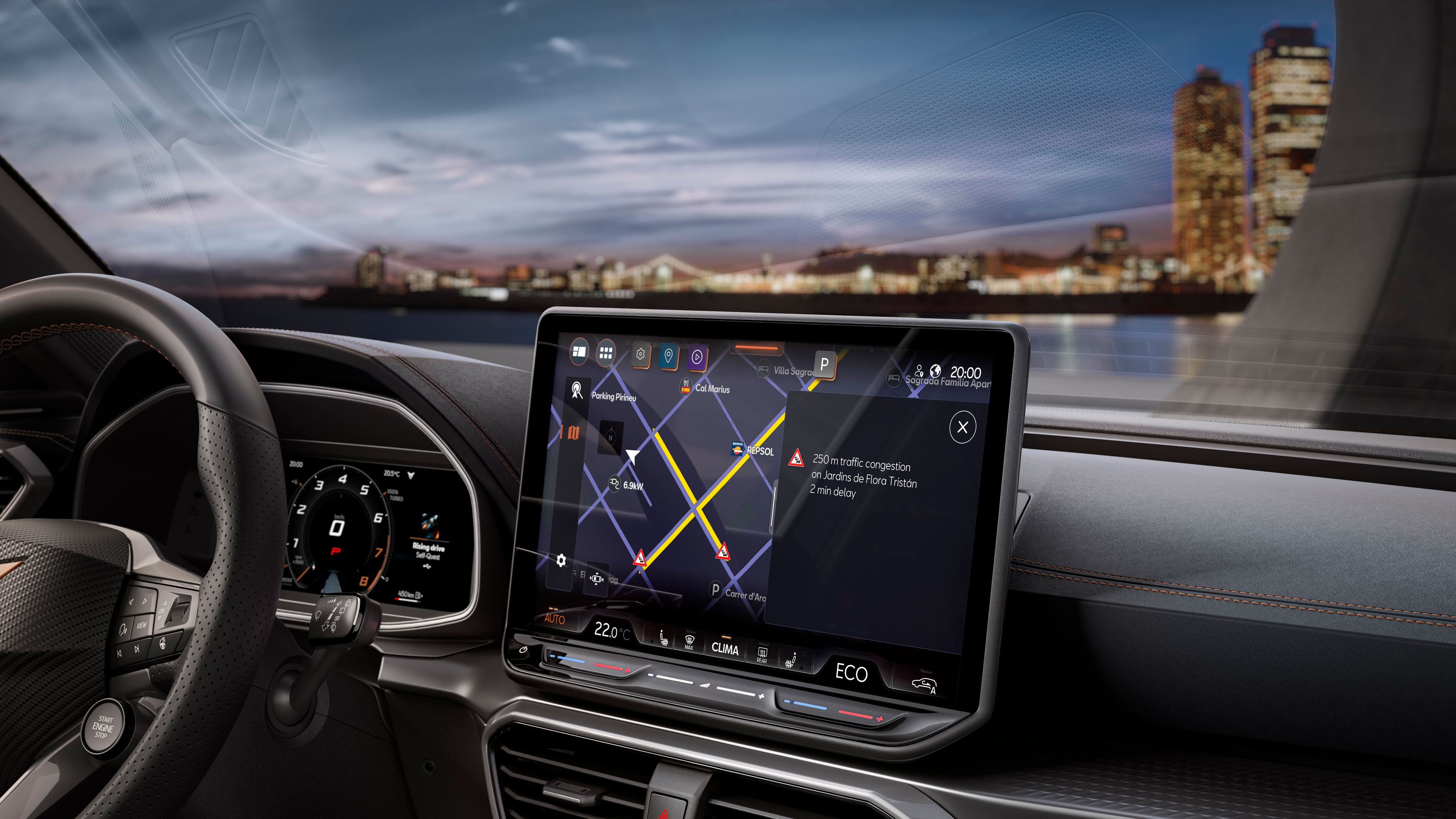 Displej systému infotainment v palubnej doske s aktívnou navigáciou. Cez čelné sklo je výhľad nočnú panorámu mesta s výškovými budovami.