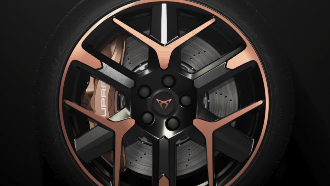 Detailný záber na koleso automobilu, zložené z čierneho disku s bronzovými prvkami. Perforovaný brzdový kotúč a nápis "Cupra" na brzdovom strmeni sú viditeľné.