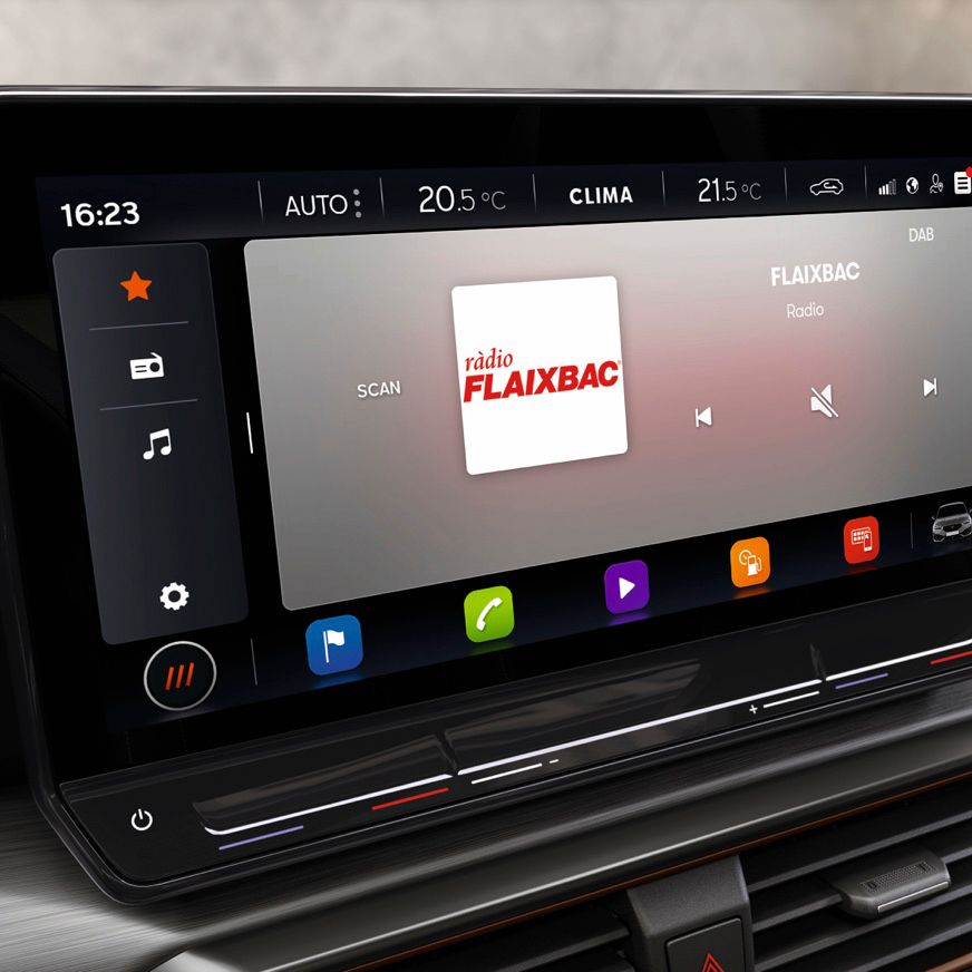 Rádio FLAIXBAC je zobrazené na displeji infotainment. Na displeji je viditeľný aktuálny čas, teplota, nastavenie klimatizácie a rôzne ovládacie prvky. Sú tam ikony pre hudbu, mapy a aplikácie.