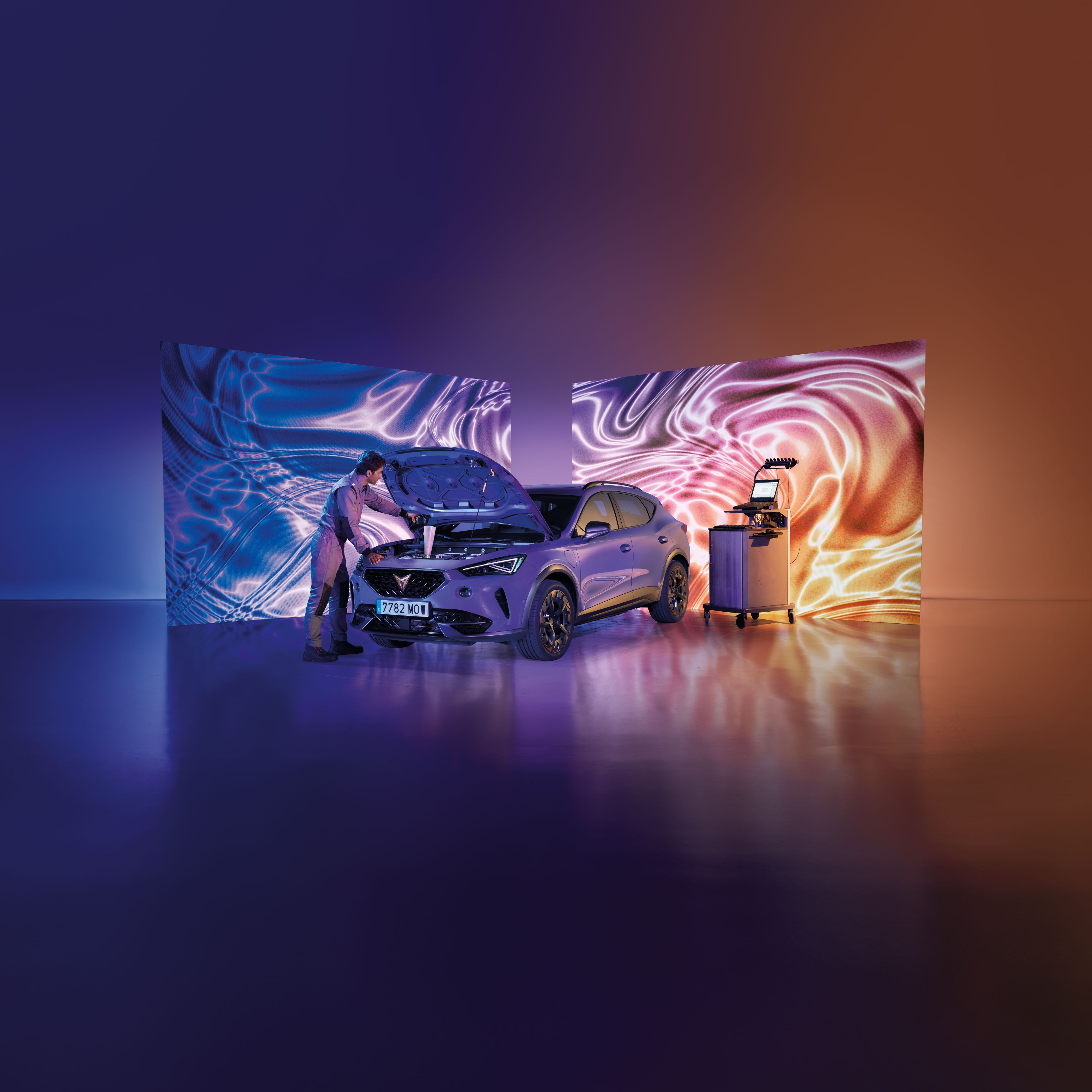 Mechanik kontroluje motor auta v modernom prostredí so svetelnými efektmi na dvoch veľkých obrazovkách. Napravo od auta sa nachádza diagnostický prístroj. Auto je v popredí, obklopené farebnými svetlami.