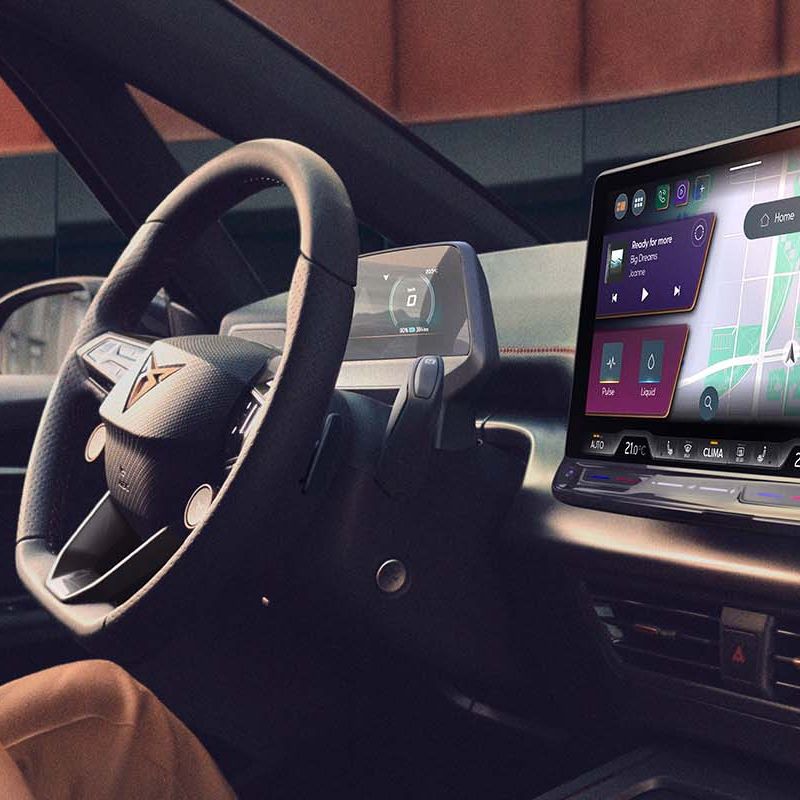 Žena sedí na sedadle vodiča a naťahuje sa. Na prednej palubnej doske sa nachádza veľká obrazovka so zobrazením navigácie.