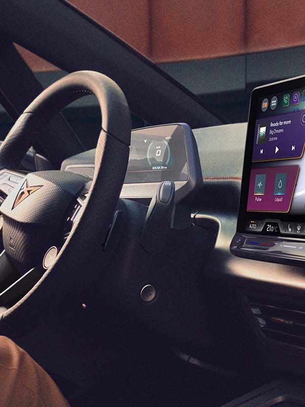 Žena sedí na sedadle vodiča a naťahuje sa. Na prednej palubnej doske sa nachádza veľká obrazovka so zobrazením navigácie.