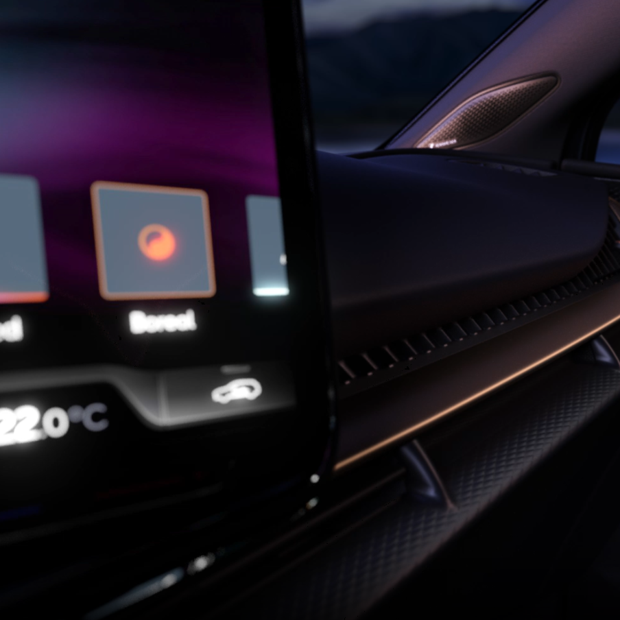 Interiér luxusného automobilu s digitálnym displejom na palubnej doske. Na obrazovke je zobrazená teplota 22°C. V pozadí vidieť hory pri západe slnka.