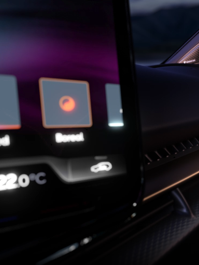 Interiér luxusného automobilu s digitálnym displejom na palubnej doske. Na obrazovke je zobrazená teplota 22°C. V pozadí vidieť hory pri západe slnka.