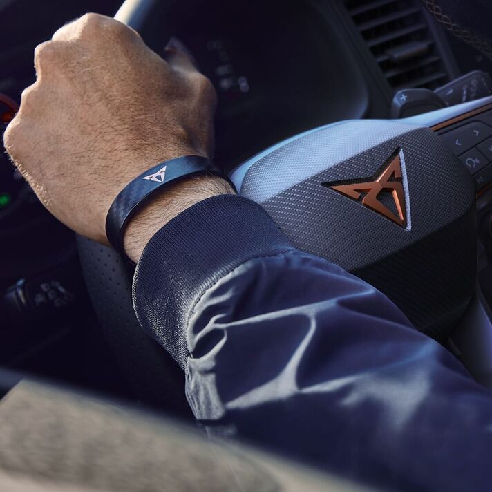 Pohľad na ruku vodiča s náramkom s logom CUPRA, ktorou drží volant modelu CUPRA.