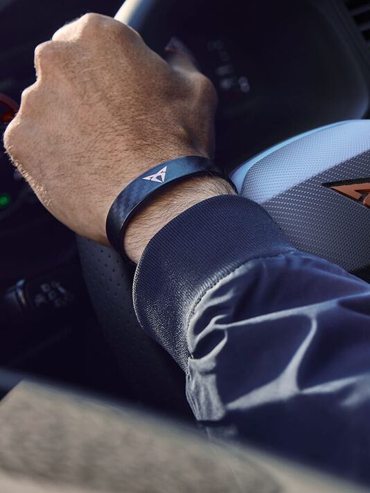 Pohľad na ruku vodiča s náramkom s logom CUPRA, ktorou drží volant modelu CUPRA.
