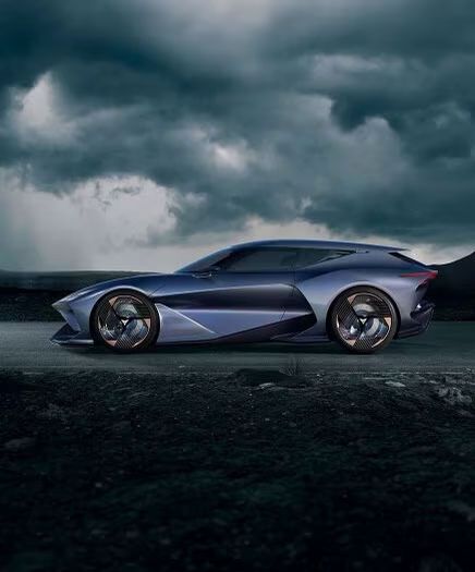 Moderné športové auto zaparkované na tmavej ceste pod zamračenou oblohou. Vyniká futuristickým dizajnom a lesklými kolesami. V pozadí sa nachádza horská krajina.