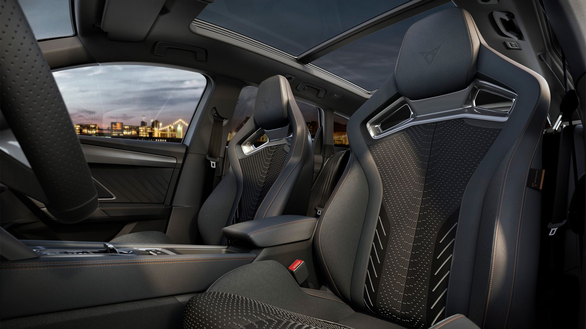 Interiér športového automobilu s dvoma prednými športovými sedadlami s výraznými vzormi. Čiastočne vidieť panoramatické okno.