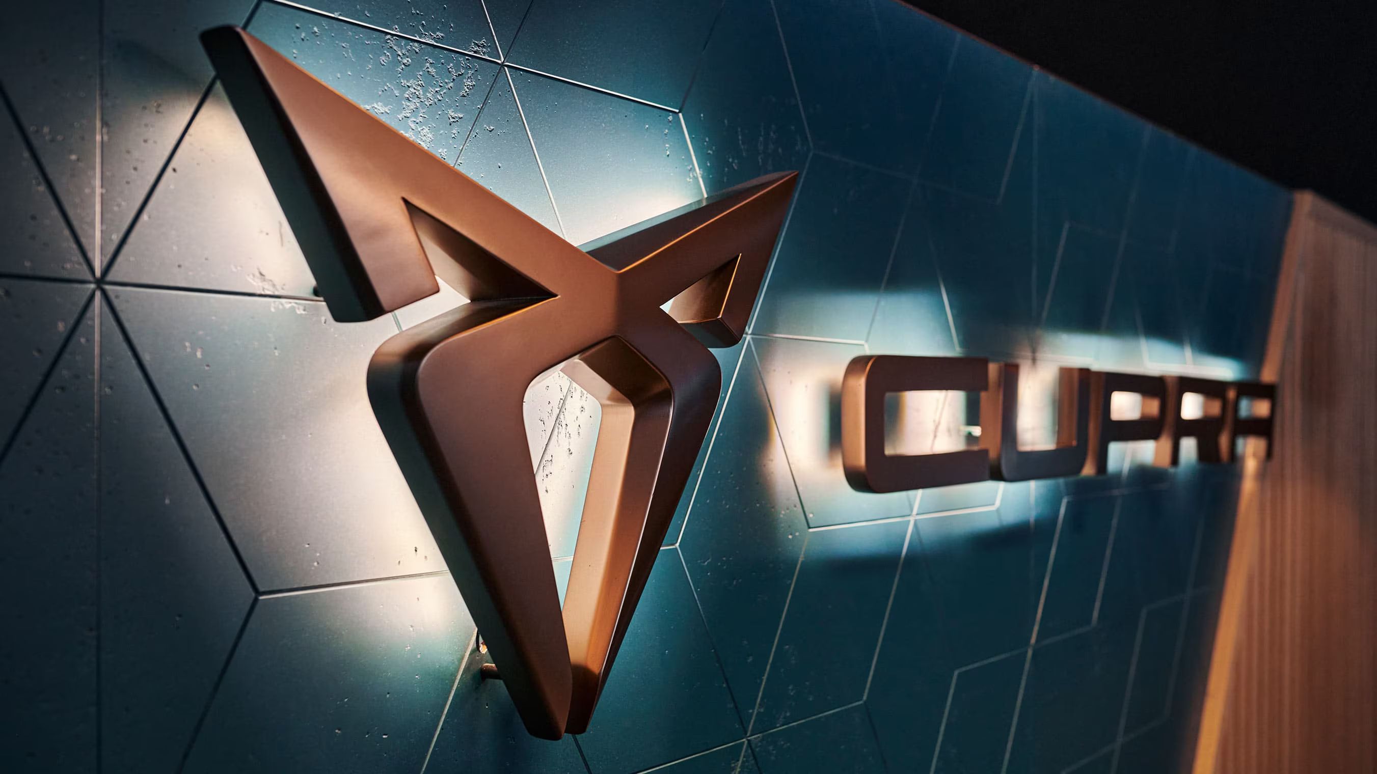 Logo a nápis CUPRA na modrej stene s dizajnovým obkladom.