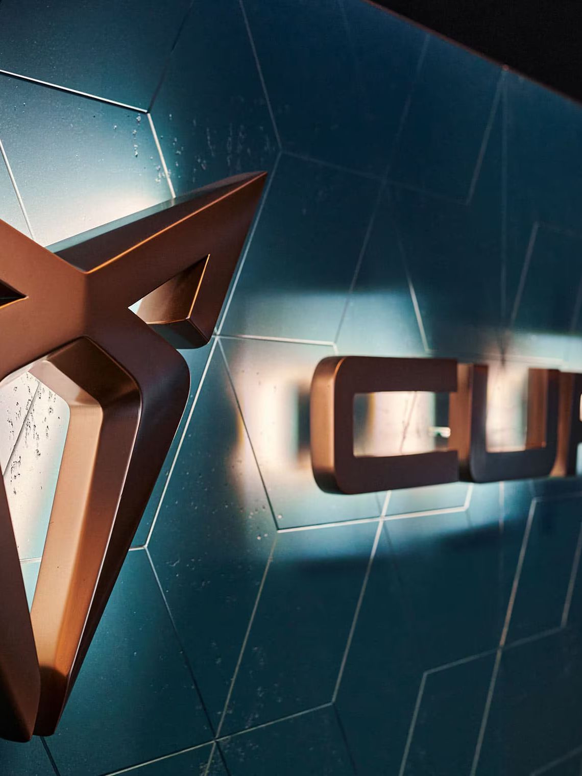 Logo a nápis CUPRA na modrej stene s dizajnovým obkladom.