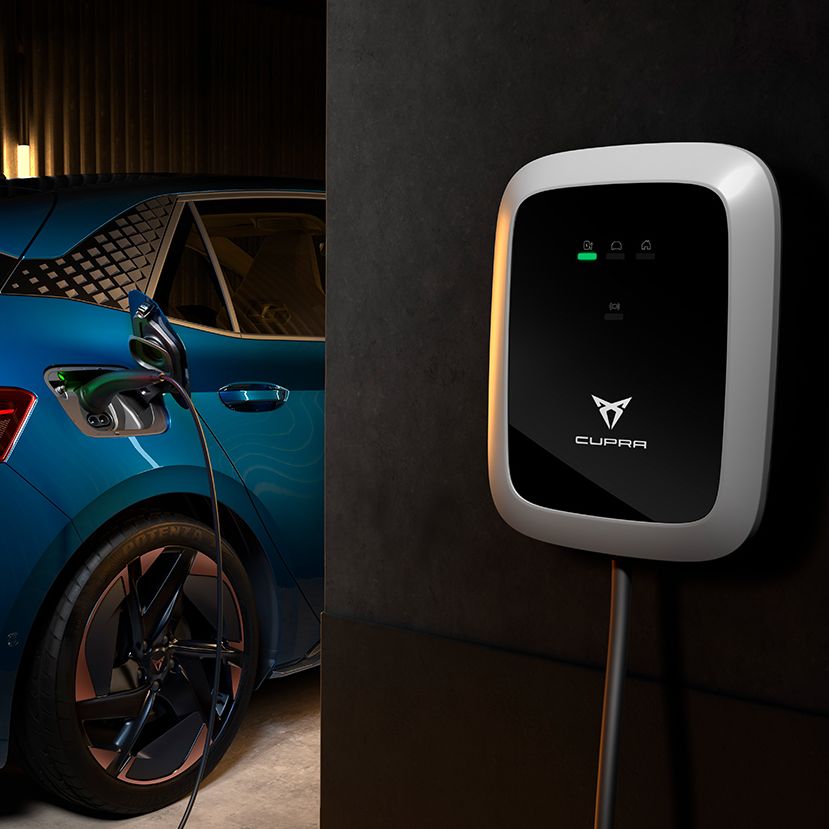 Nabíjacia stanica CUPRA je pripojená k modrému elektrickému autu cez nabíjací kábel v garáži. Nabíjacia stanica zobrazuje stav nabíjania pomocou LED diód.
