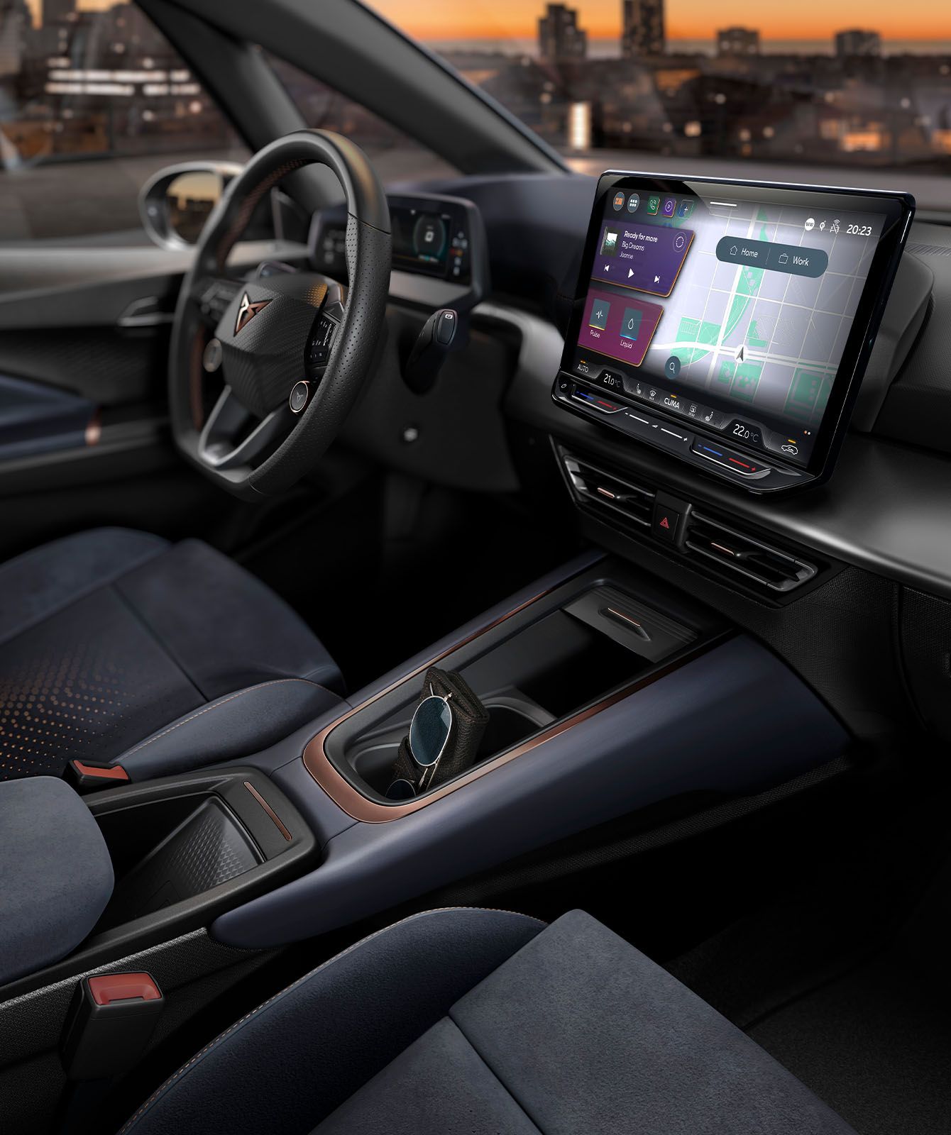 Interiér moderného auta so zameraním na palubnú dosku s veľkým dotykovým displejom. Autosedadlá sú čalúnené tmavo modrou látkou. V pozadí je panoráma mesta pri západe slnka.