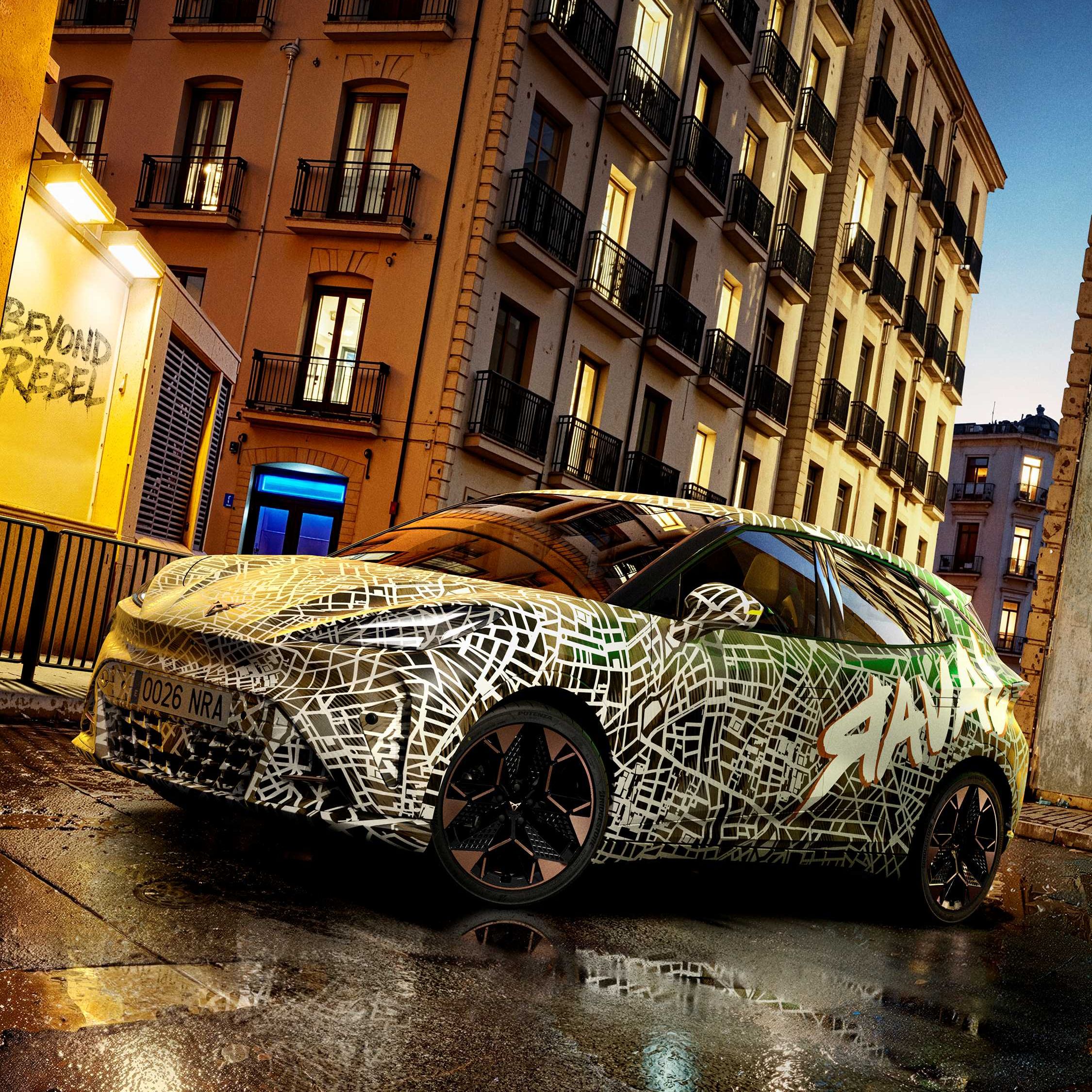 Kamuflovaný model CUPRA stojí na mokrej ceste pred historickou budovou za súmraku.