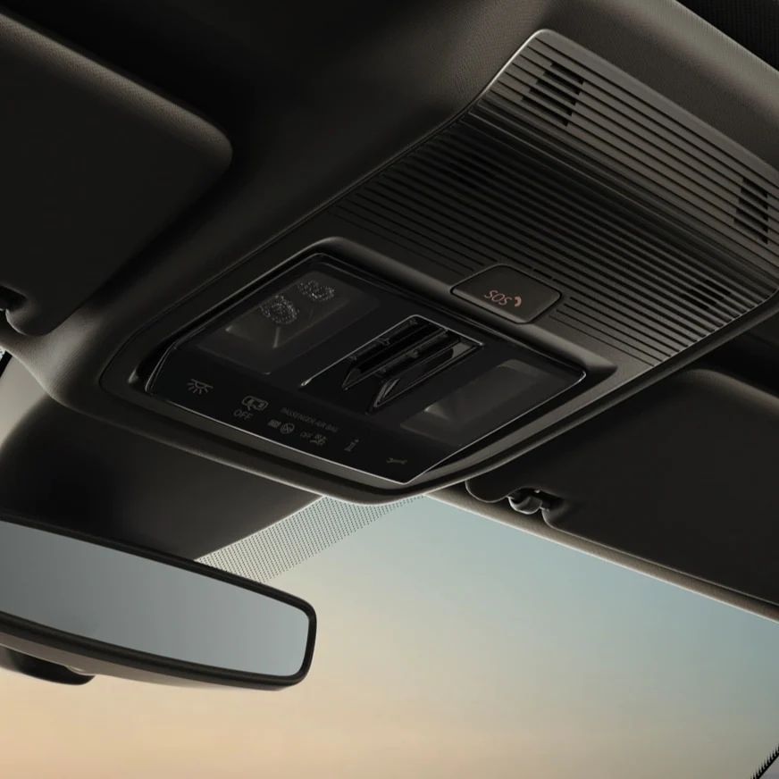 Stropný ovládací panel vozidla vrátane tlačidla núdzového volania. Plasty sú čierne.