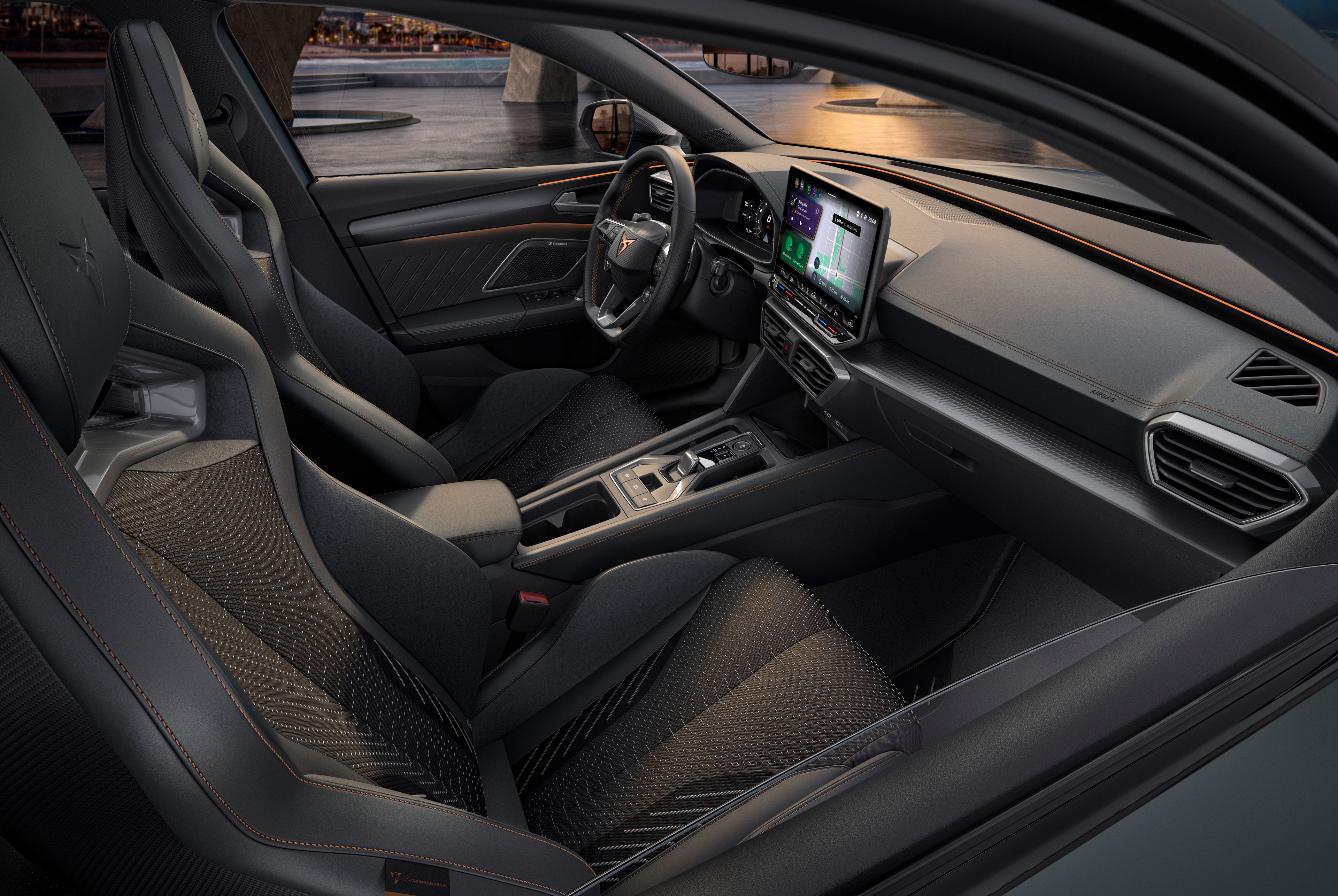 Luxusný interiér športového automobilu s modernou palubnou doskou, veľkým dotykovým displejom a vysoko kvalitnými sedadlami. Čierne sedadlá majú oranžové stehy. Do interiéru dopadá svetlo cez okná vozidla.