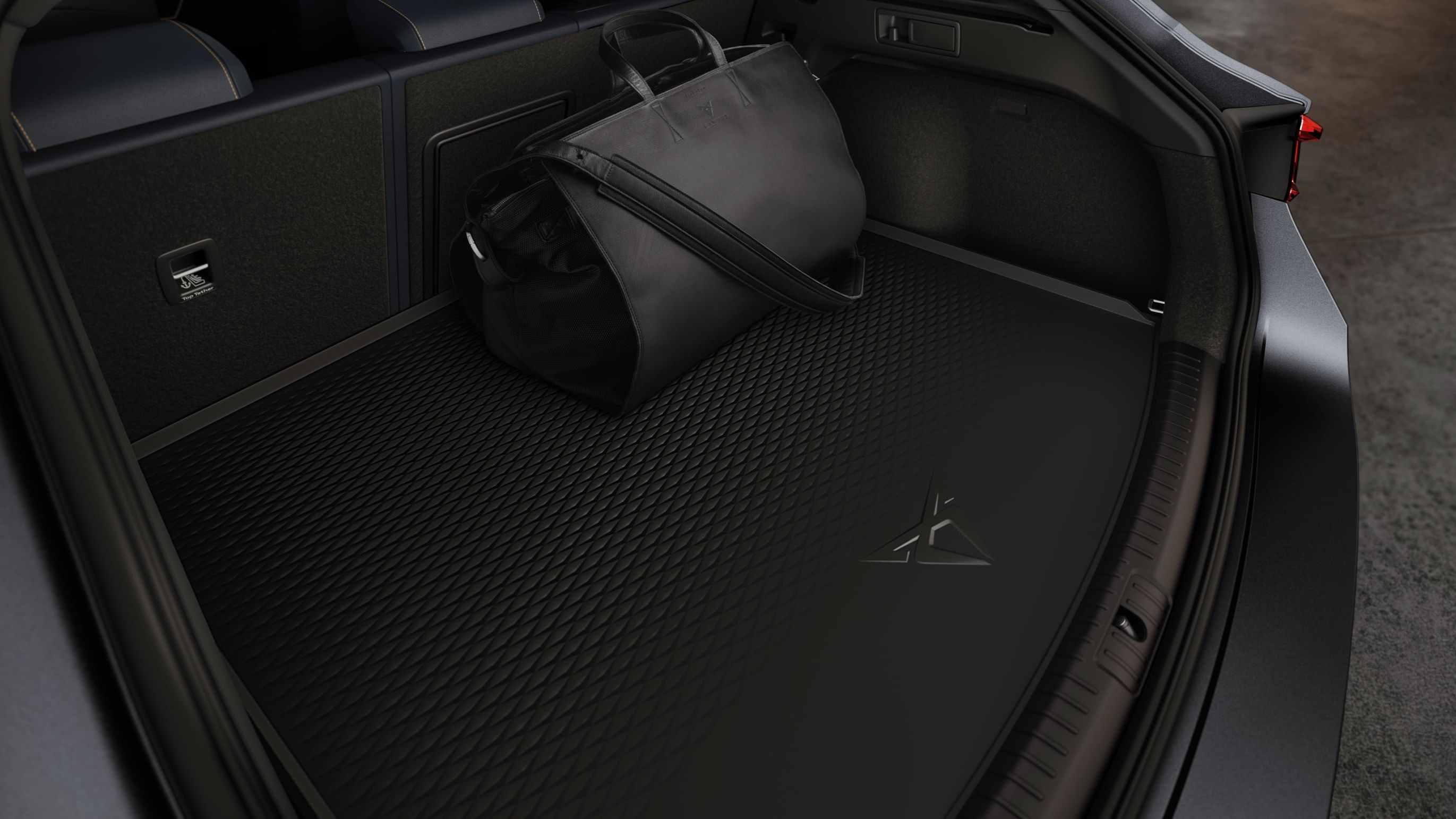 Čierna športová taška uložená v batožinovom priestore s gumenou vaničkou. Batožinový priestor je priestranný.