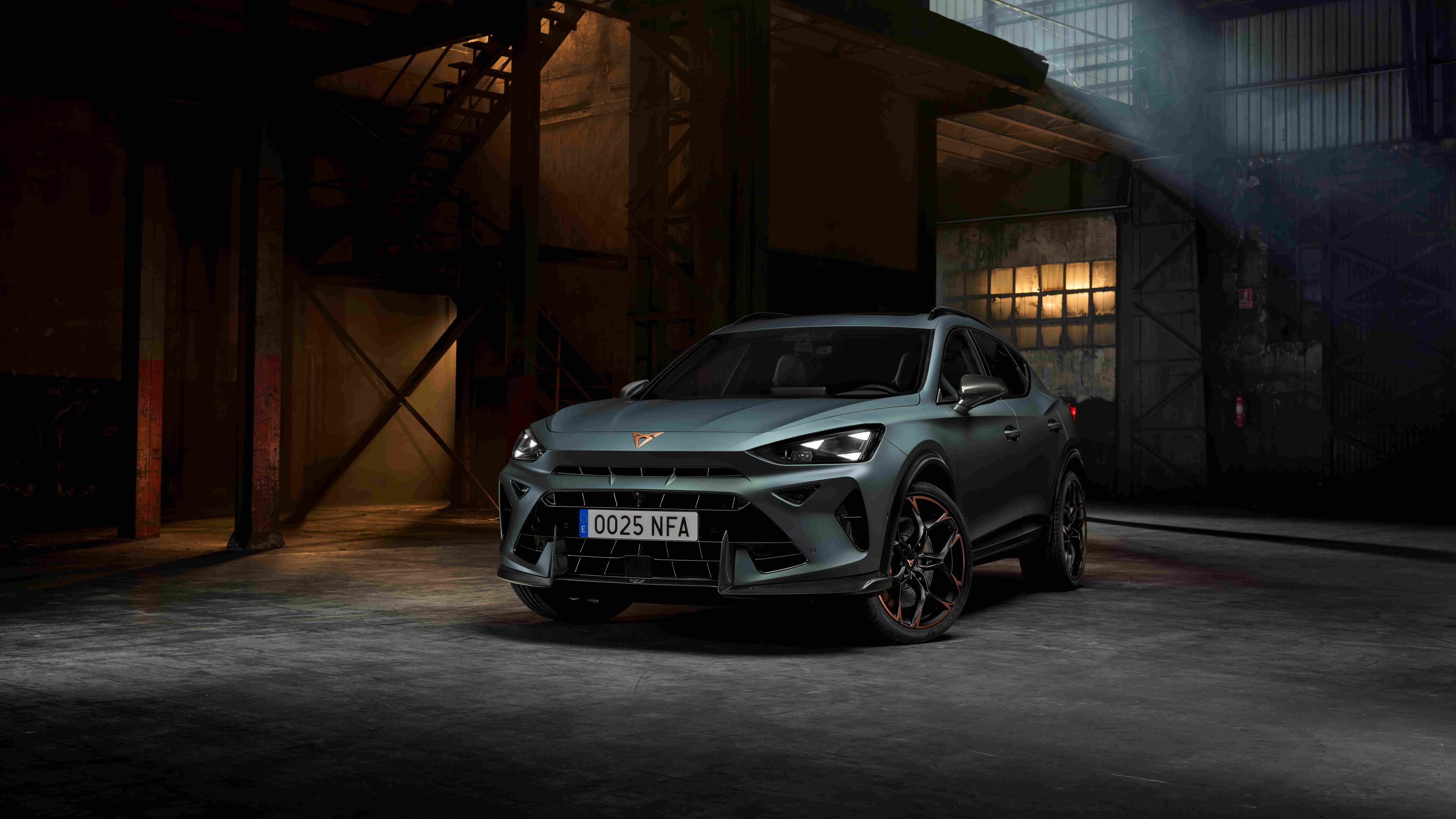 CUPRA Dormentor v zelenej farbe stojí v industriálnom prostredí s nepriamym osvetlením. Športový vzhľad auta podčiarkujú výrazné svetlá a aerodynamické línie. 