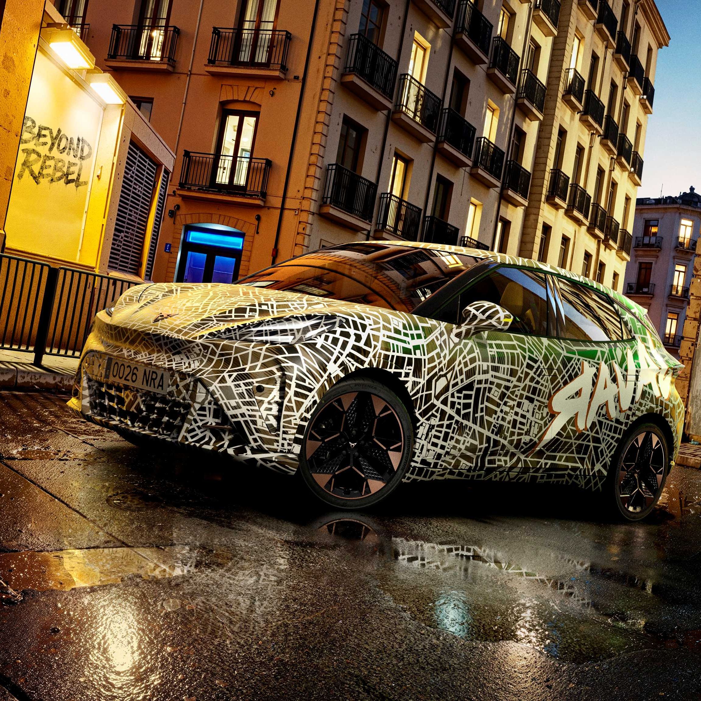Kamuflovaný model CUPRA stojí na mokrej ceste pred historickou budovou za súmraku.