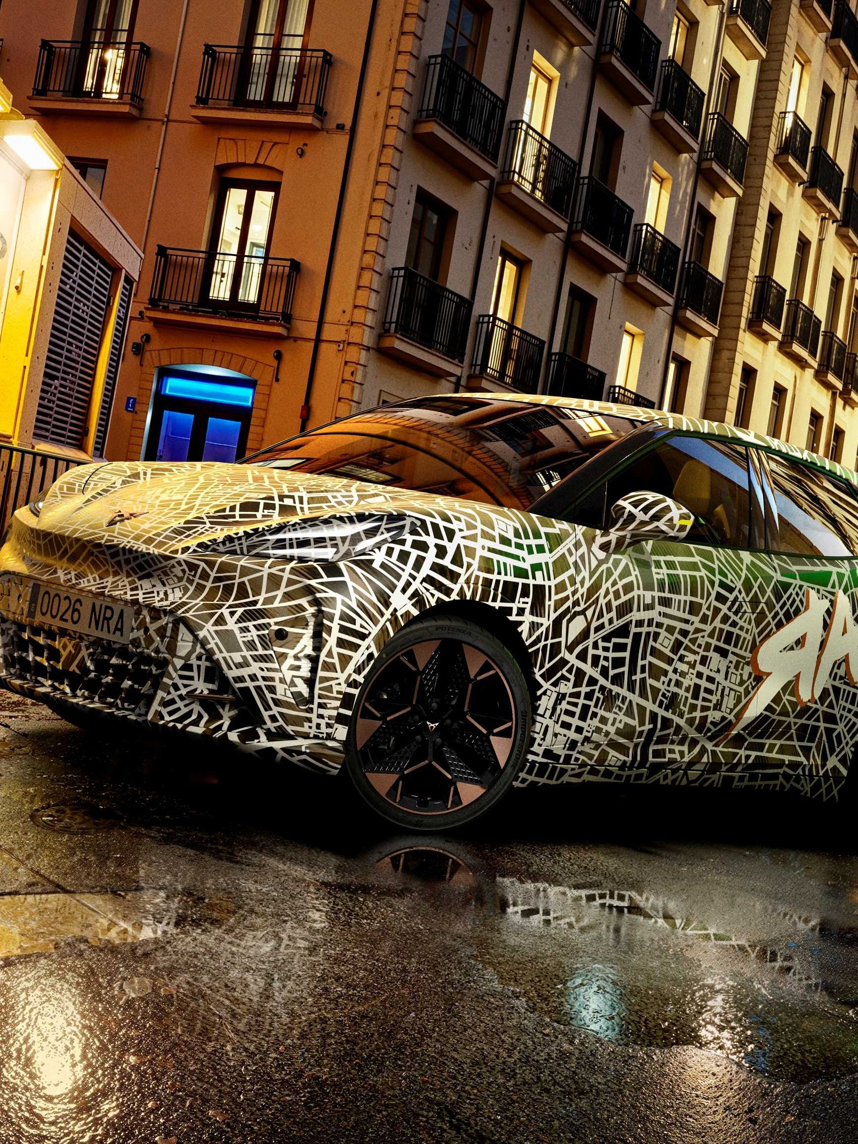 Kamuflovaný model CUPRA stojí na mokrej ceste pred historickou budovou za súmraku.