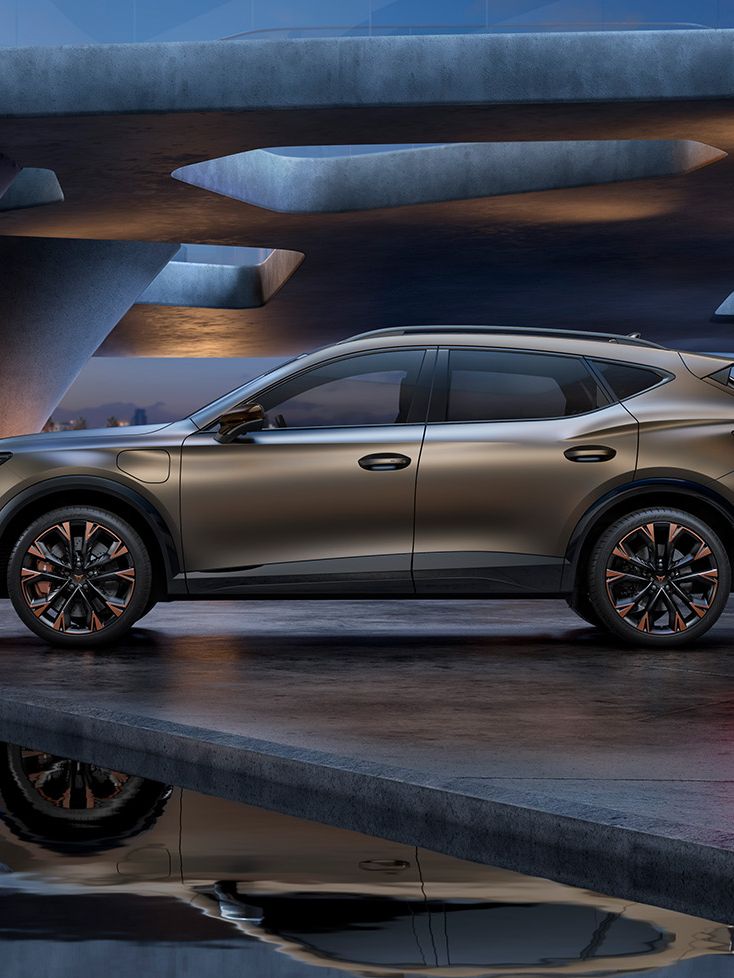 Moderné SUV zaparkované na betónovej ploche s odrazom v blízkej vodnej hladine. Pozadie tvorí futuristická stavba s oblúkmi a osvetlením. Celkovo luxusná a štýlová atmosféra.