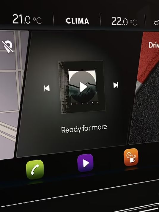 Dotykový displej vozidla zobrazuje navigáciu, prehrávanie hudby a rôzne ovládacie ikony. Na displeji je viditeľné rozhranie s mapou, ikonami na prepínanie skladieb a klimatizáciu.
