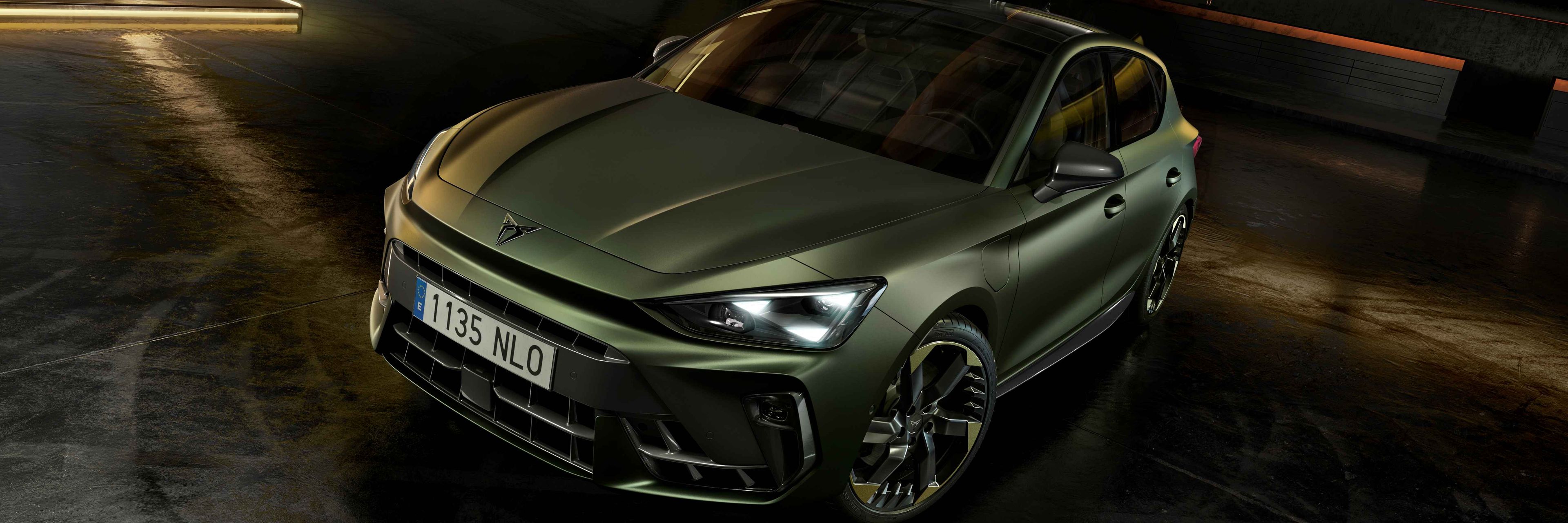 CUPRA Terramar v edícii Tribe v zelenej metalíze zaparkované v čiernom interiéri s dizajnovými LED lištami na stenách.