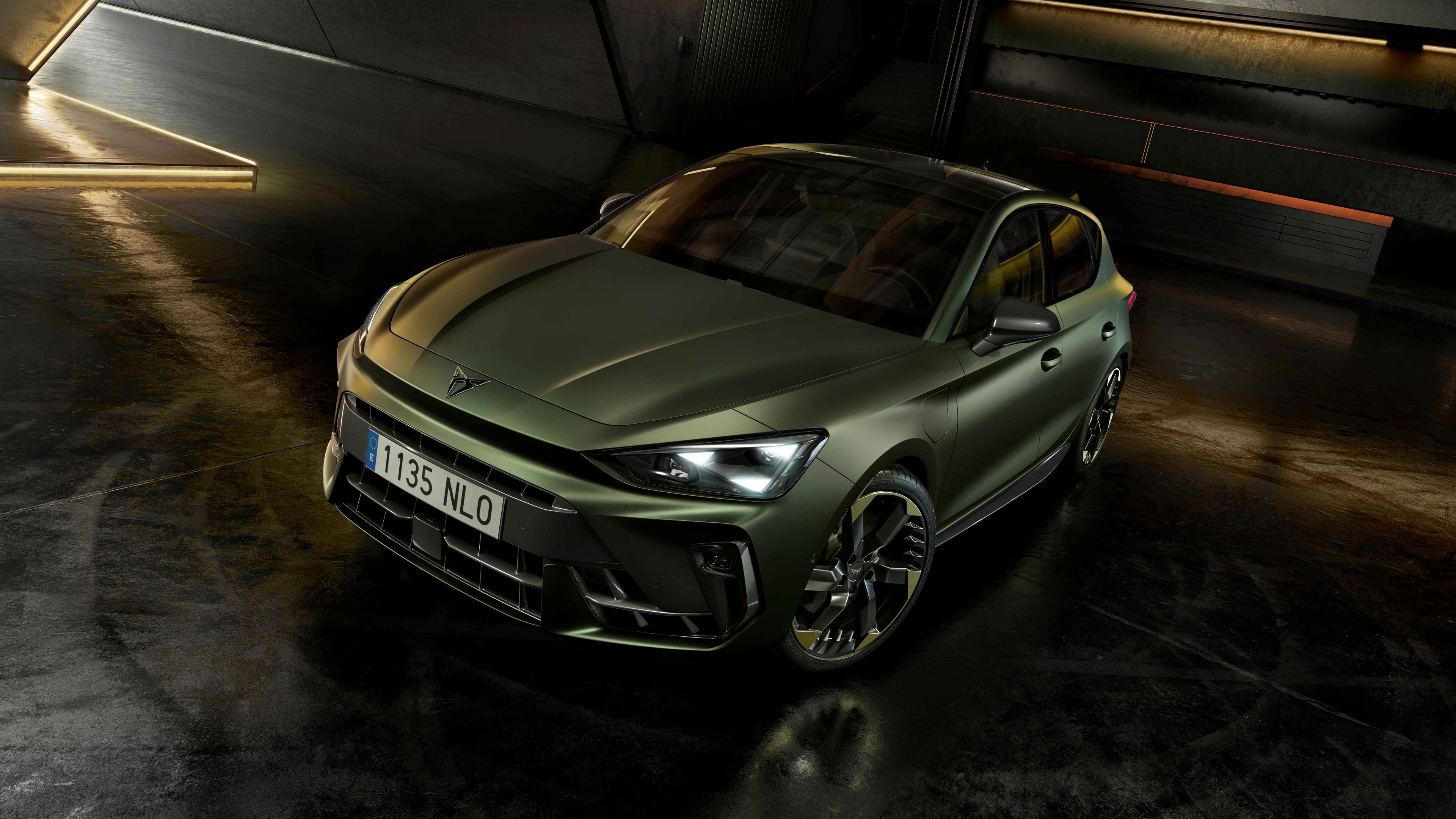 CUPRA Terramar v edícii Tribe v zelenej metalíze zaparkované v čiernom interiéri s dizajnovými LED lištami na stenách.