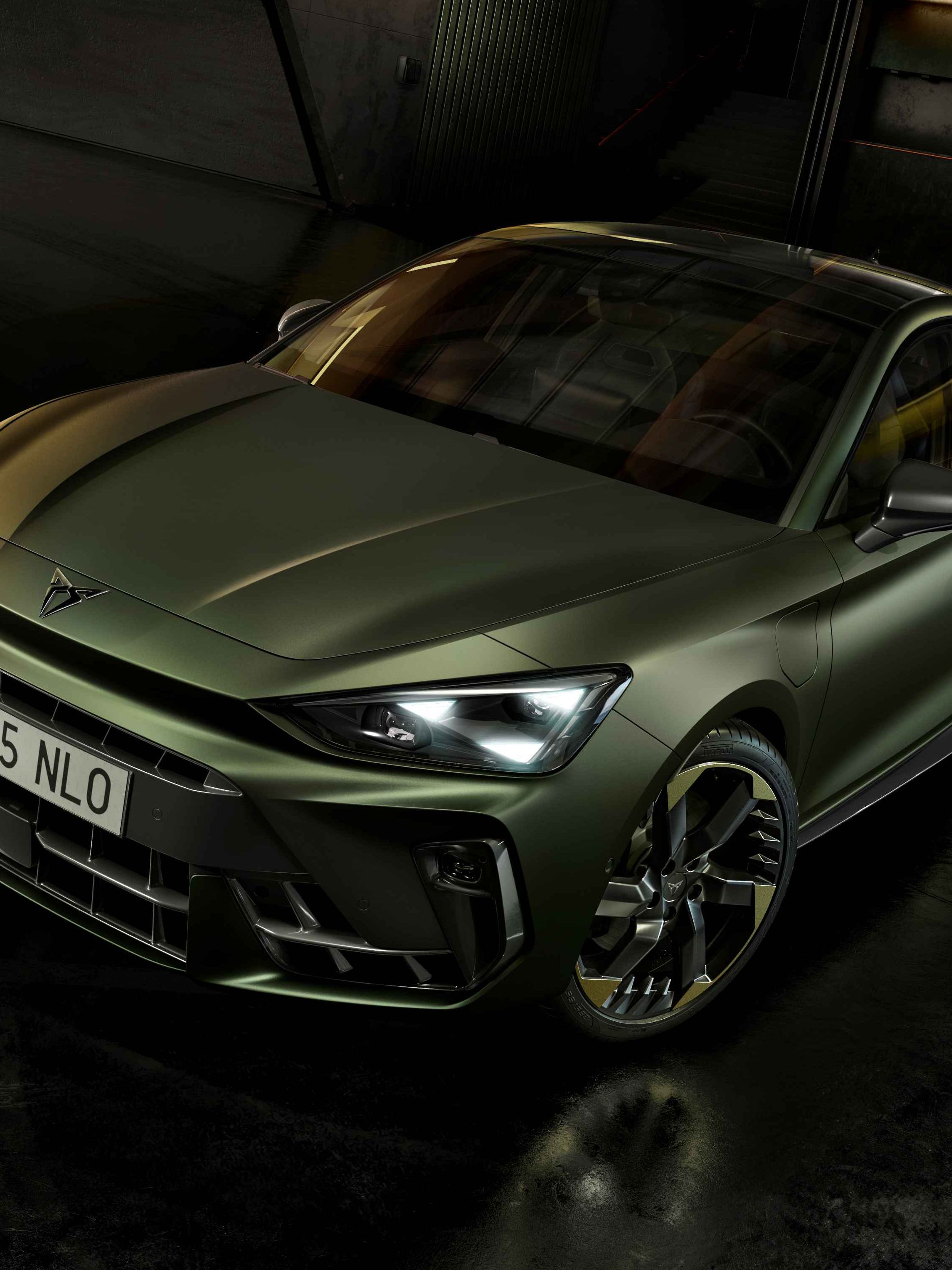 CUPRA Terramar v edícii Tribe v zelenej metalíze zaparkované v čiernom interiéri s dizajnovými LED lištami na stenách.