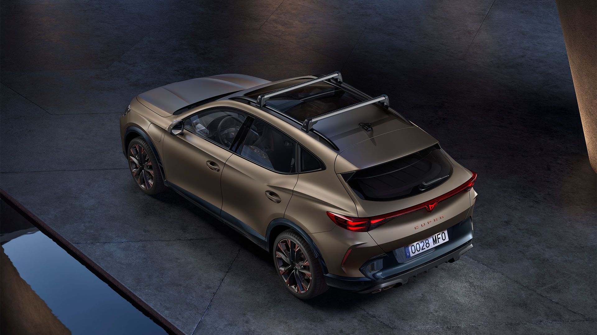 Automobil Cupra Formentor je zobrazený zhora na voľnom priestranstve. Má športový dizajn, tmavé okná a strešný nosič.