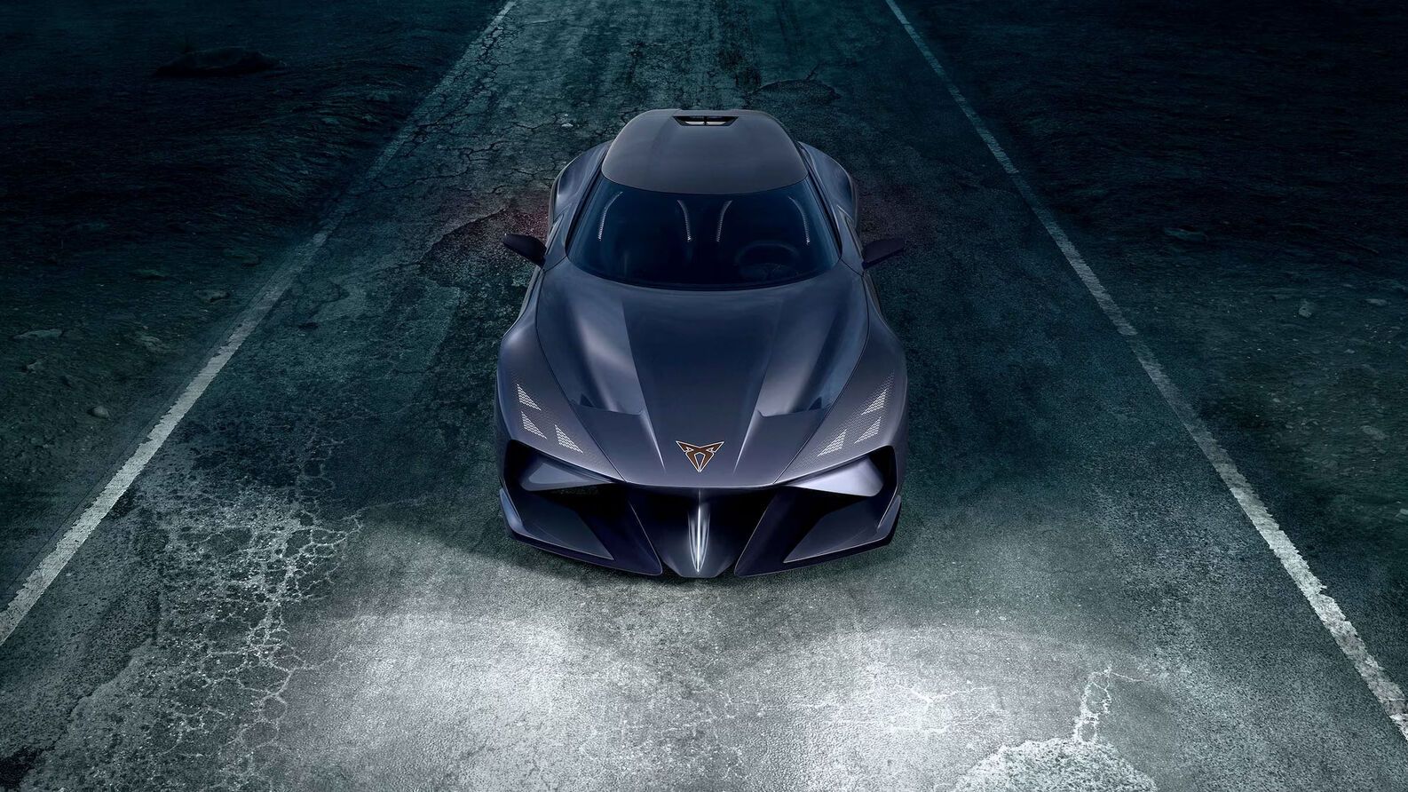 Moderné športové auto spredu na tmavej, opustenej ceste. Auto má aerodynamický dizajn a ostré línie. Svetlá auta sú zapnuté a osvetľujú cestu pred ním.