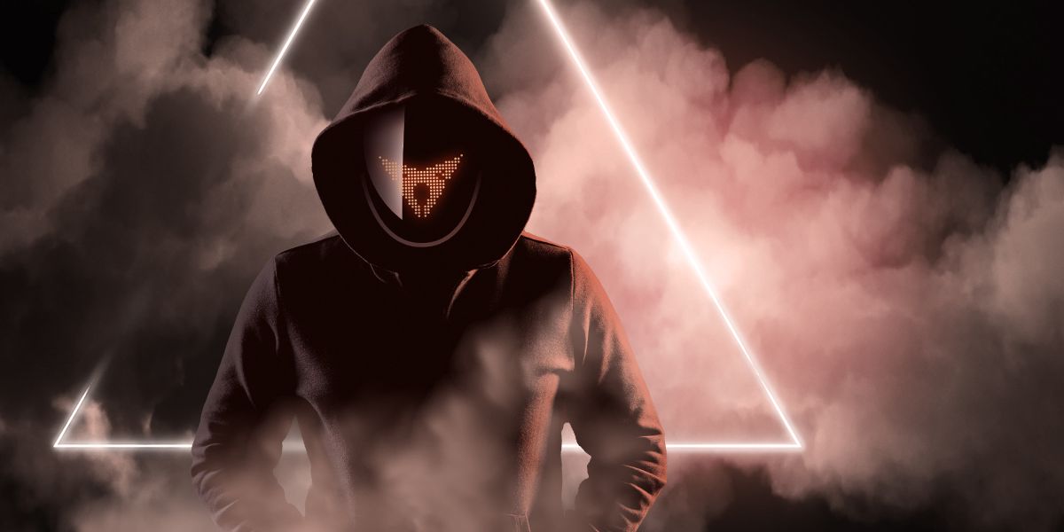 Osoba v tmavej mikine s kapucňou stojí pred svetelným trojuholníkom, ktorý je obklopený hmlou. Nie je vidieť celú tvár, len masku s logom CUPRA a kapucňu. Atmosféra pôsobí tajomne.