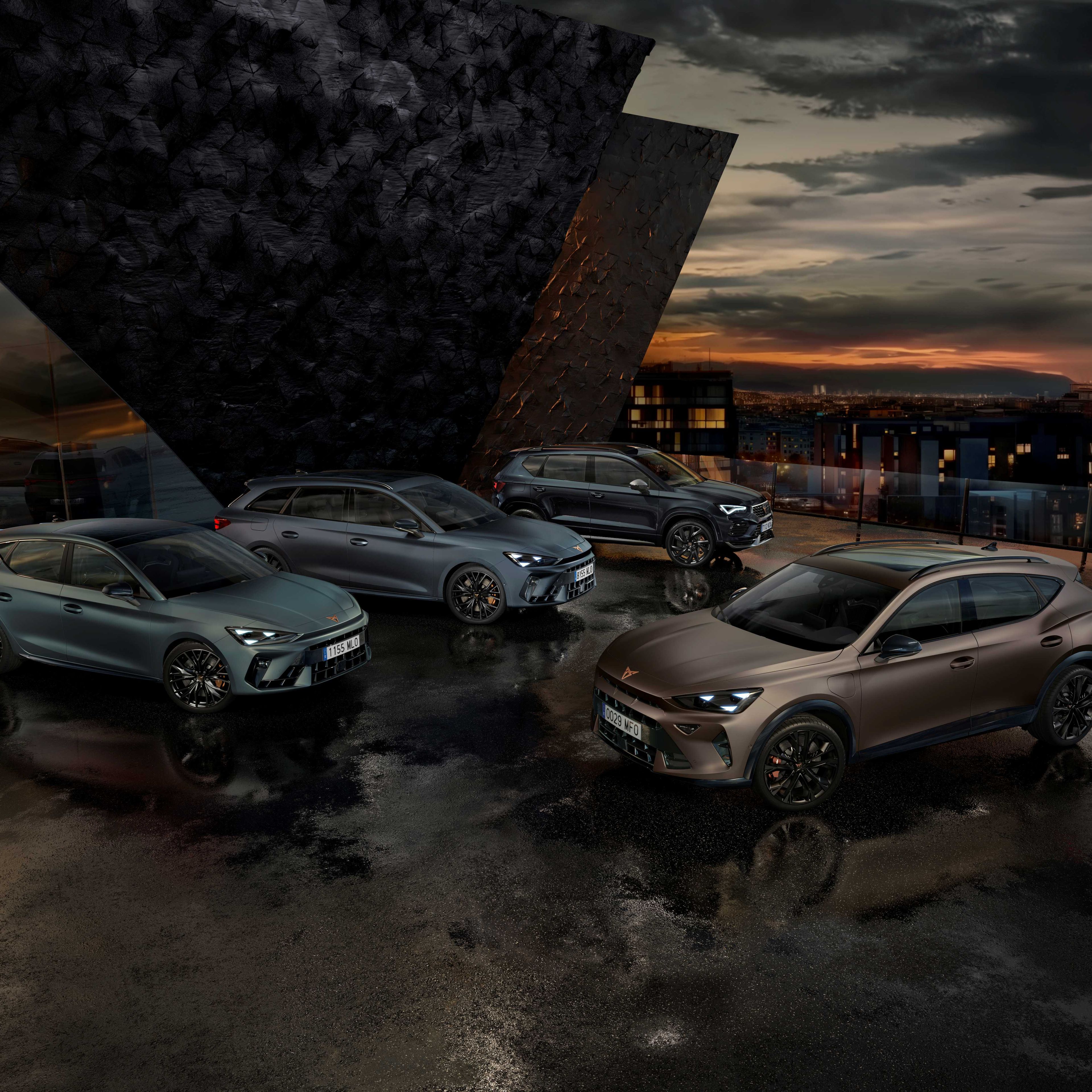 Na obrázku sú štyri autá značky Cupra zaparkované vedľa moderného architektonického objektu počas súmraku. Každé auto má športový dizajn a tmavé metalické farby. Pozadie tvorí mestská scenéria s budovami a večerným osvetlením.