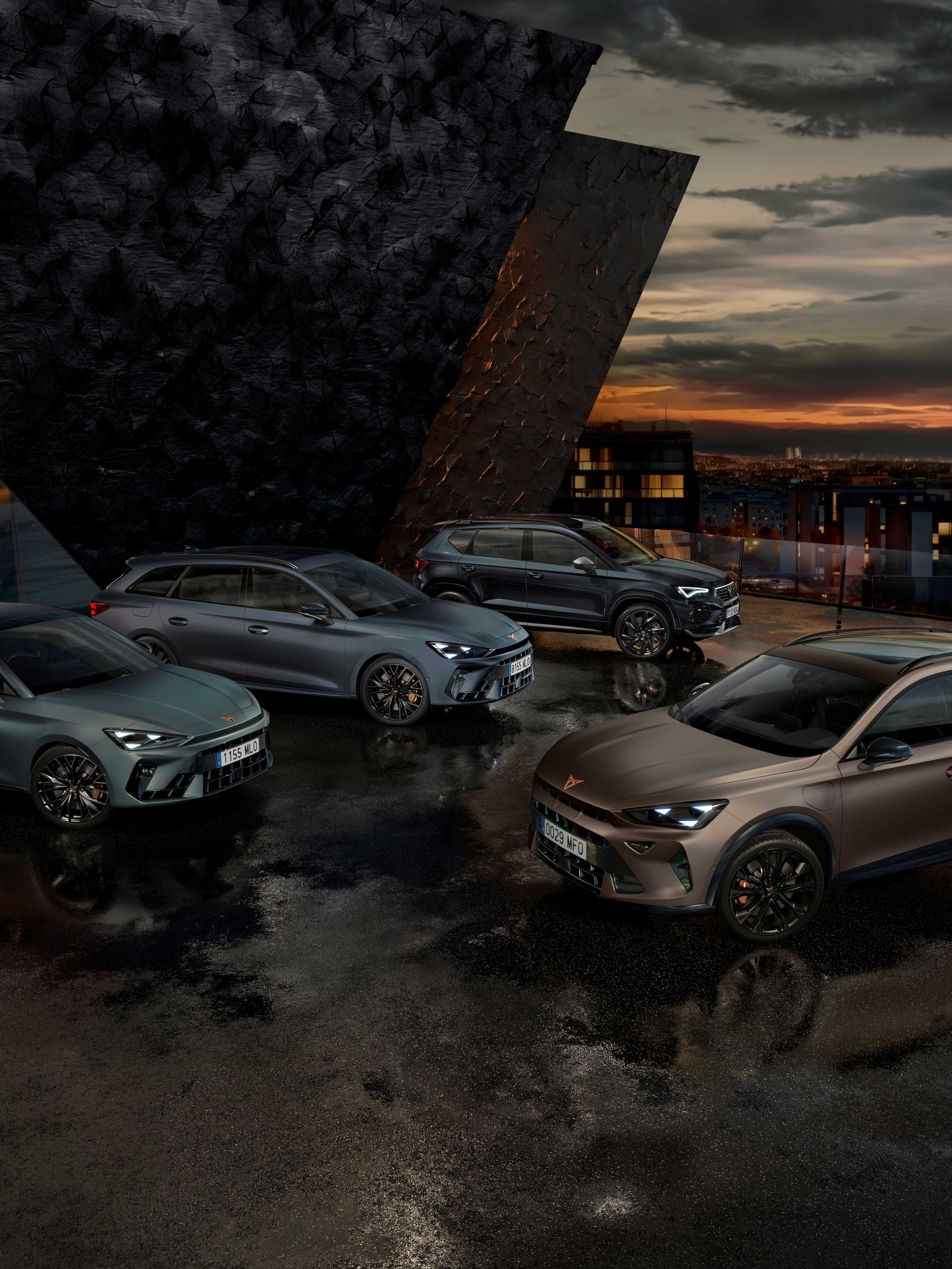 Na obrázku sú štyri autá značky Cupra zaparkované vedľa moderného architektonického objektu počas súmraku. Každé auto má športový dizajn a tmavé metalické farby. Pozadie tvorí mestská scenéria s budovami a večerným osvetlením.