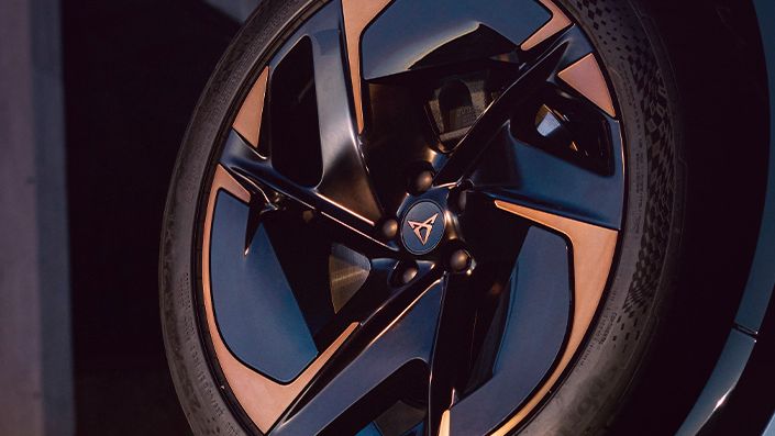 Koleso vozidla s moderným dizajnom disku, vedľa stojí osoba s rozmazanou tvárou.