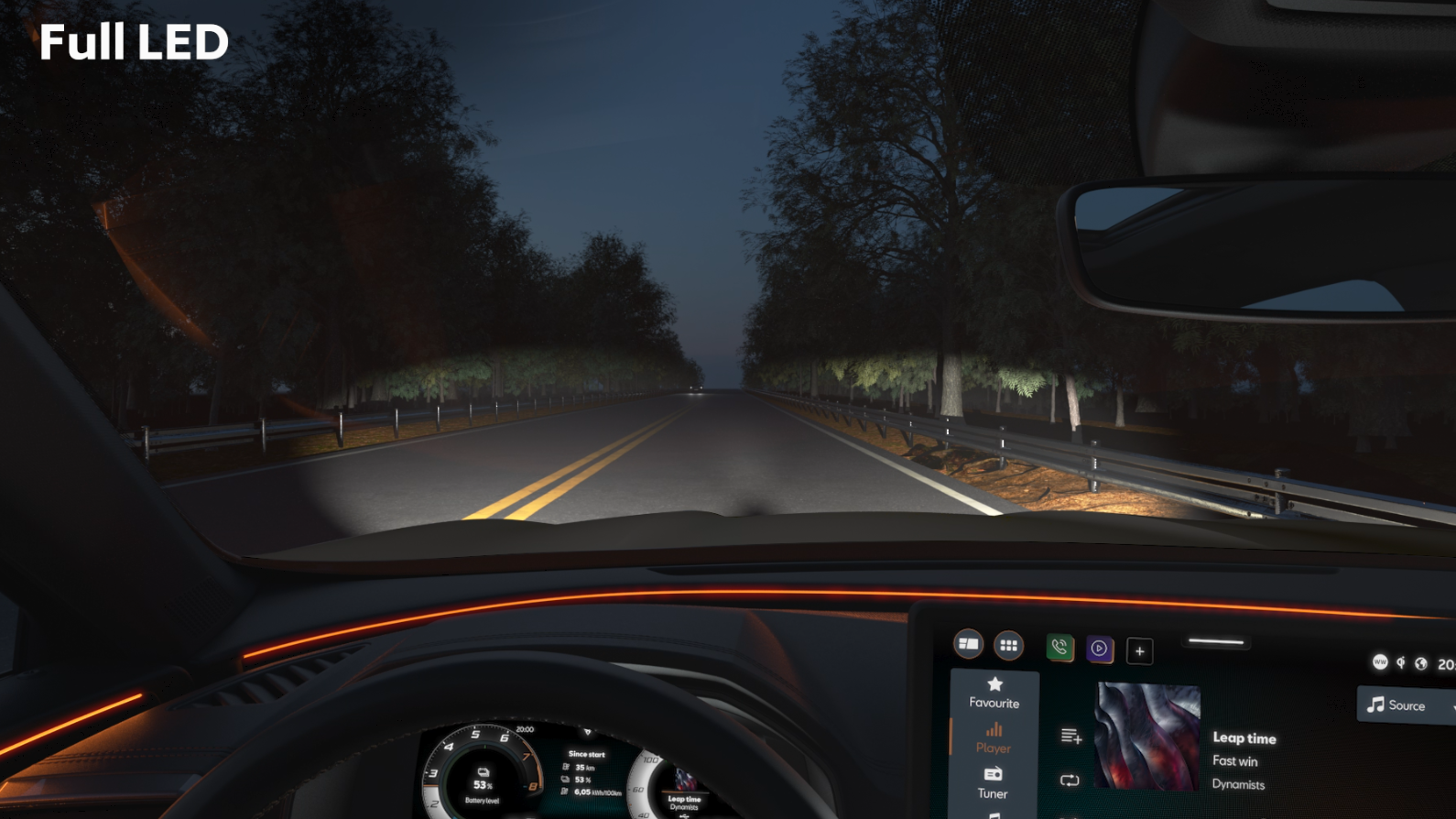 Pohľad z interiéru auta na osvetlenú cestu v noci. Vpredu vidieť displej so zobrazením rádia. Cestu lemujú stromy na oboch stranách.