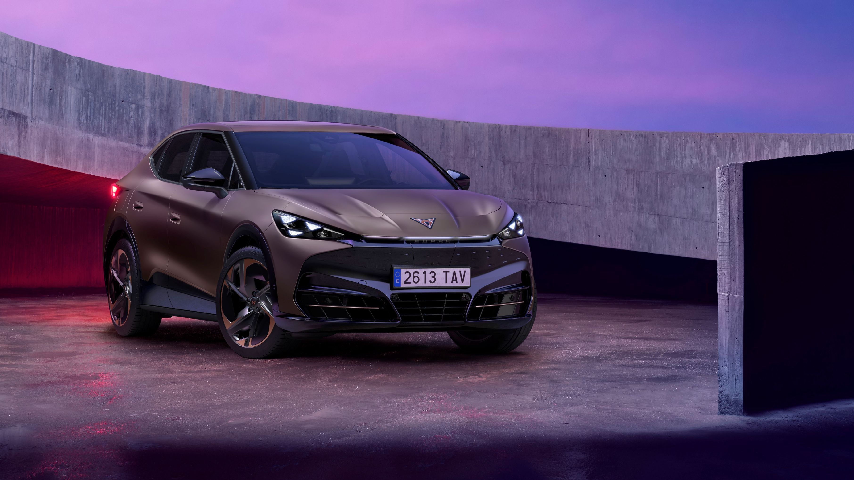 CUPRA Tavadcan zaparkovaný na betónovej ploche vedľa betónovej lávky. Obrázok dotvára ružový filter. 