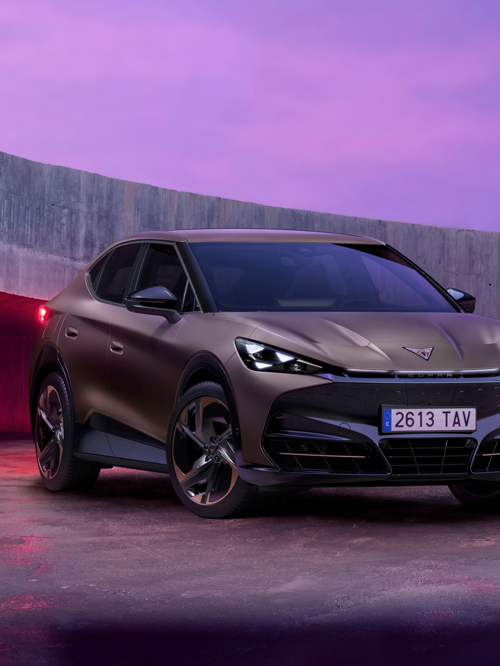 CUPRA Tavadcan zaparkovaný na betónovej ploche vedľa betónovej lávky. Obrázok dotvára ružový filter. 