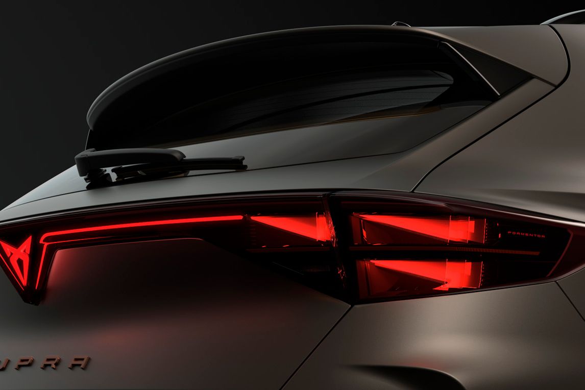Pohľad na zadné partie modelu CUPRA, kde vidíme svietiace zadné svetlá s osvetleným logom CUPRA, zadné okno so stieračom a strešný spojler.
