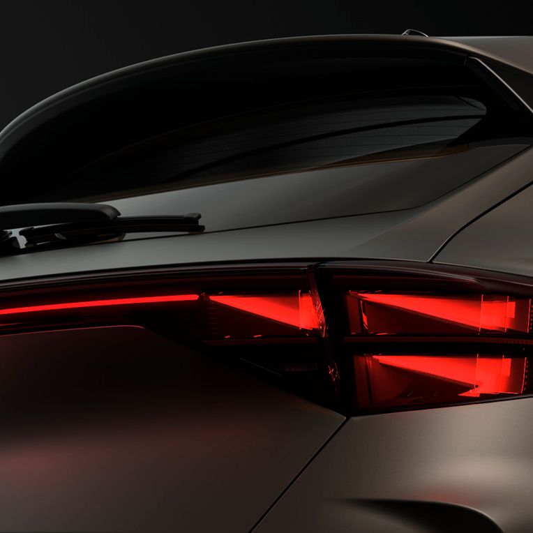 Pohľad na zadné partie modelu CUPRA, kde vidíme svietiace zadné svetlá s osvetleným logom CUPRA, zadné okno so stieračom a strešný spojler.