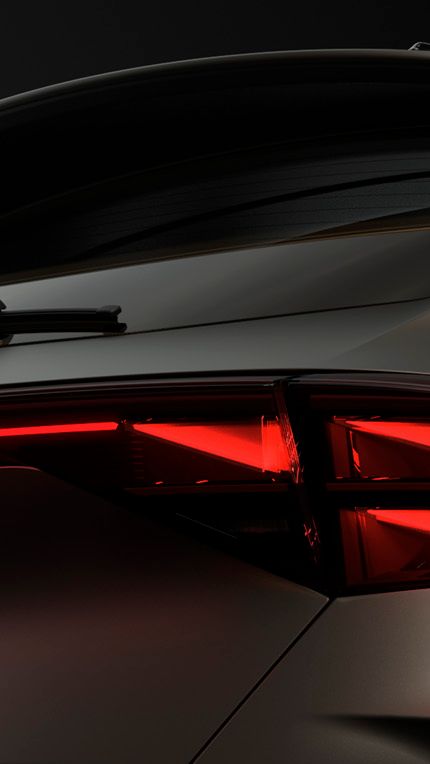 Pohľad na zadné partie modelu CUPRA, kde vidíme svietiace zadné svetlá s osvetleným logom CUPRA, zadné okno so stieračom a strešný spojler.