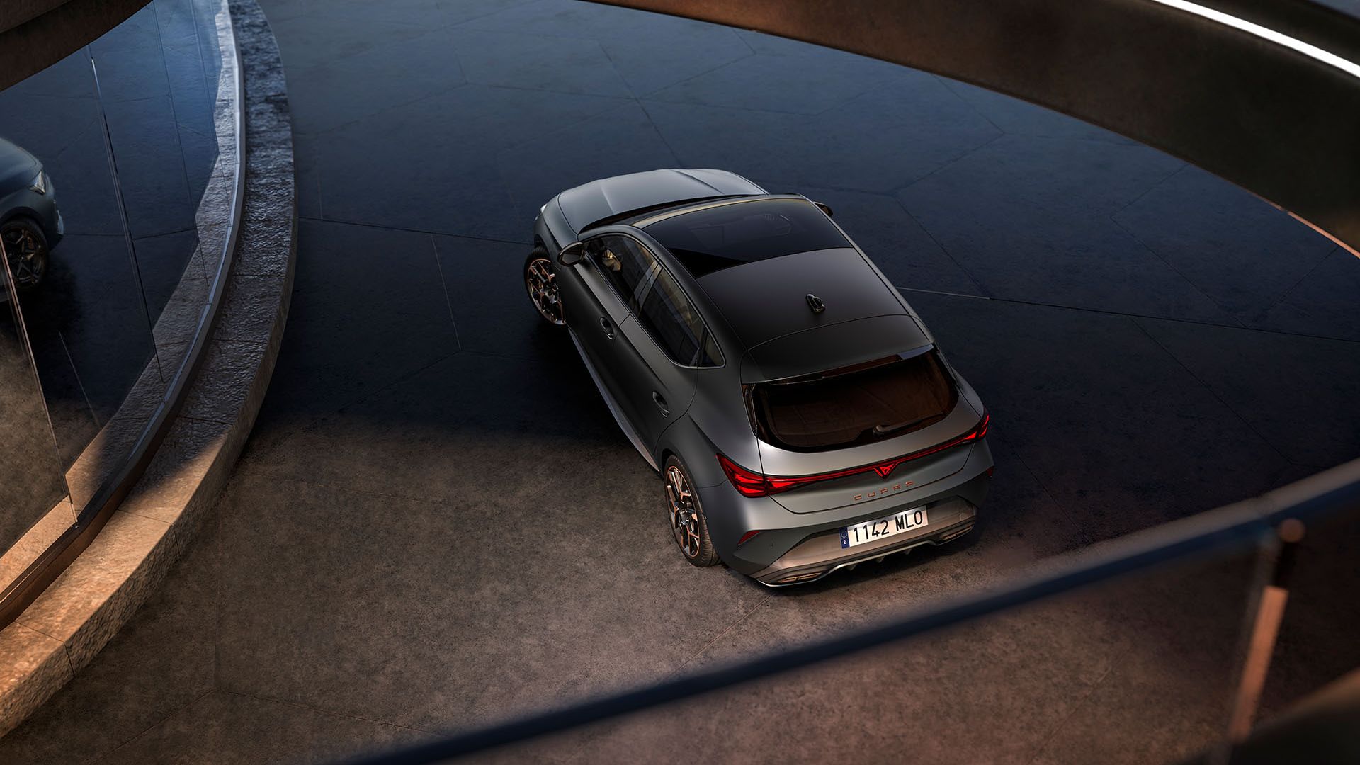 CUPRA Leon zaparkovaný pred sklenenou stenou modernej, futuristickej budovy.