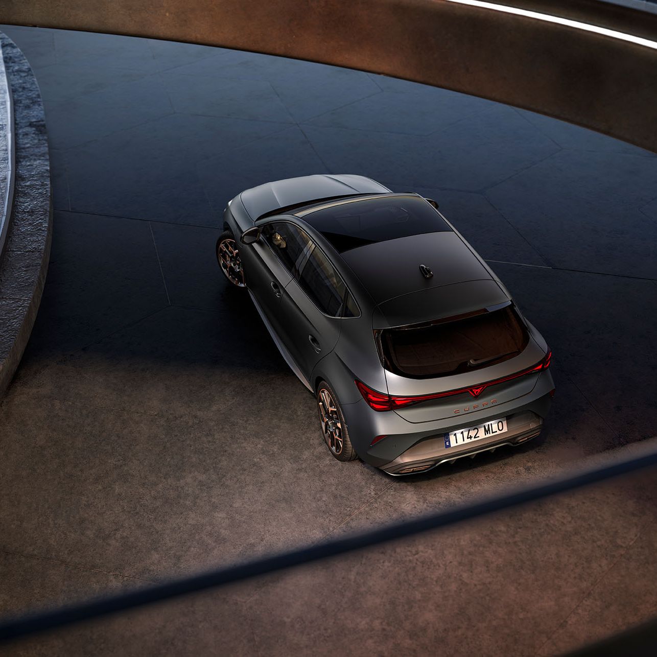 CUPRA Leon zaparkovaný pred sklenenou stenou modernej, futuristickej budovy.