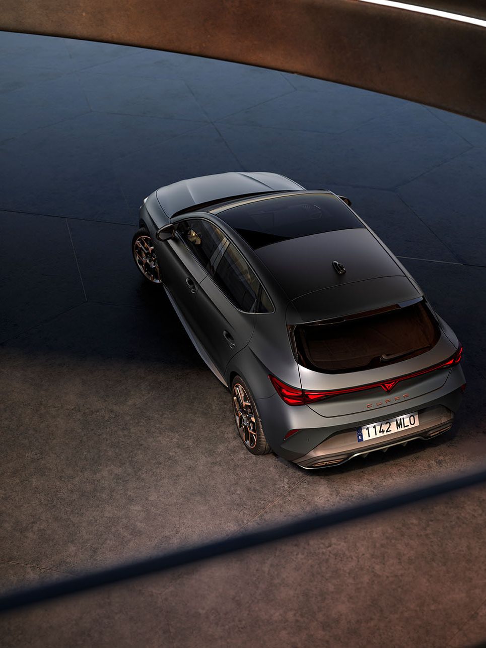 CUPRA Leon zaparkovaný pred sklenenou stenou modernej, futuristickej budovy.