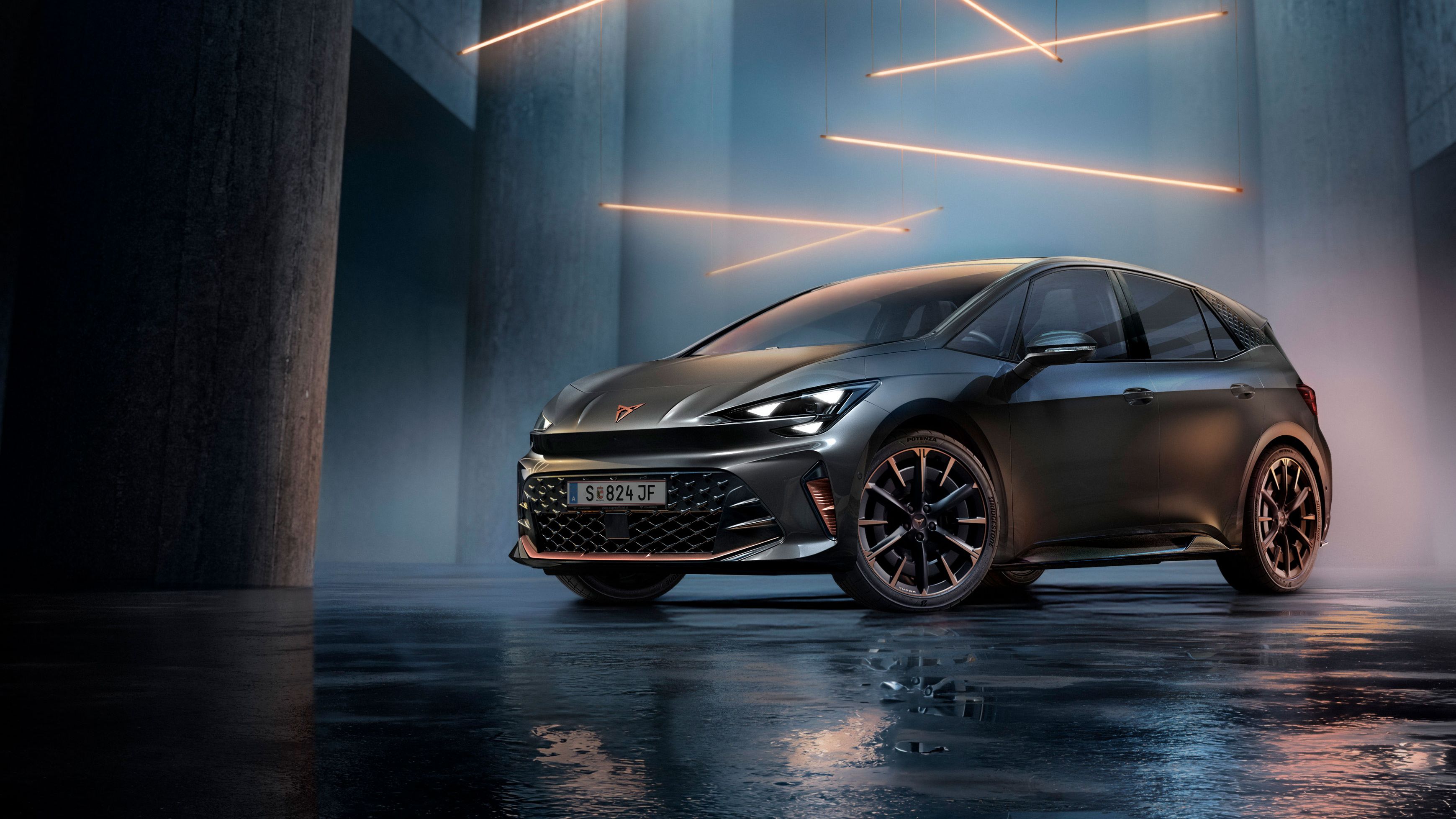 Sivé vozidlo CUPRA Born stojí v modernom, tmavom prostredí s vertikálnymi stĺpmi a svietiacimi LED pásmi. Podlaha je lesklá a odráža vozidlo aj osvetlenie. Auto pôsobí mohutne a elegantne.