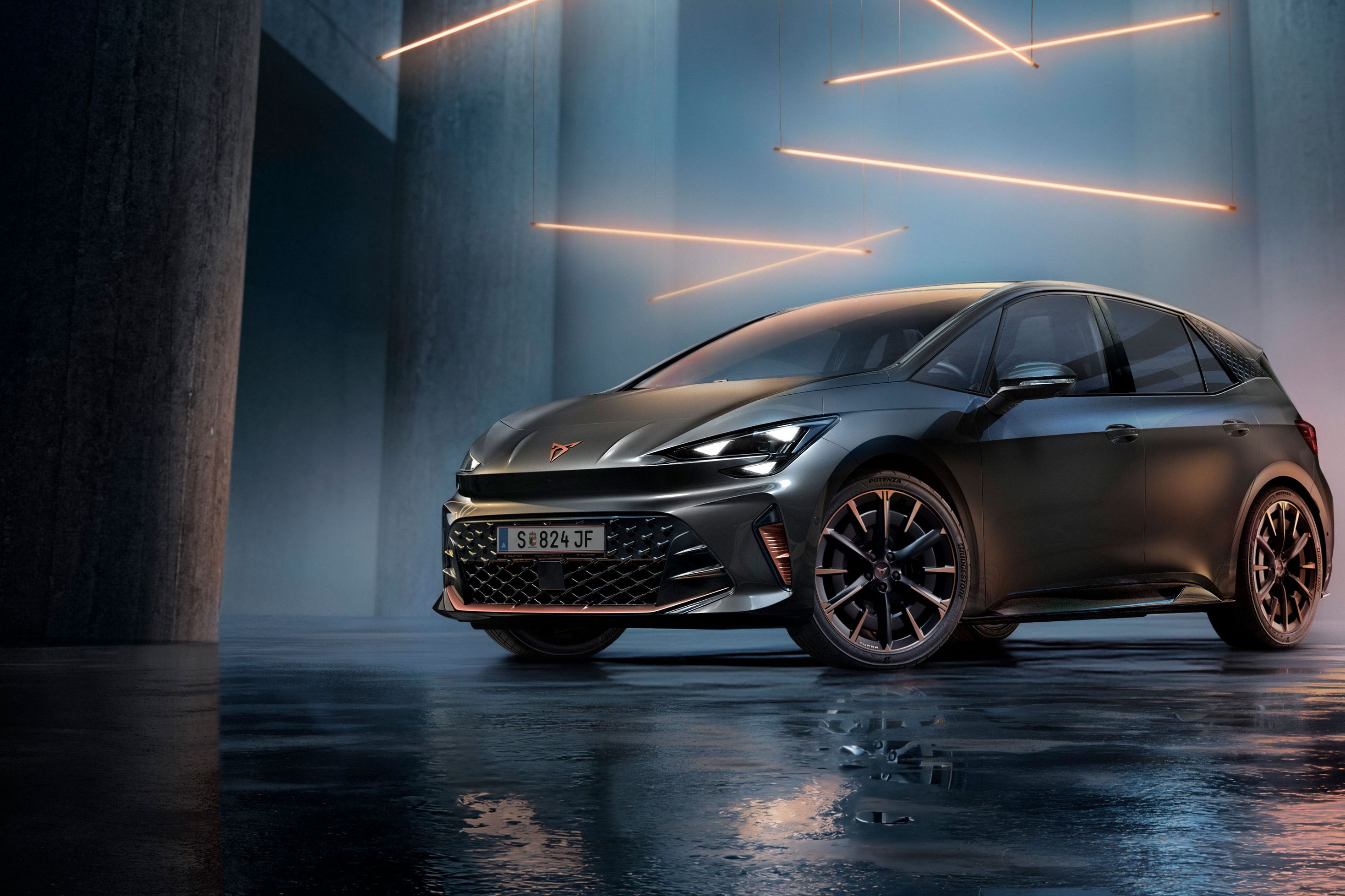 Sivé vozidlo CUPRA Born stojí v modernom, tmavom prostredí s vertikálnymi stĺpmi a svietiacimi LED pásmi. Podlaha je lesklá a odráža vozidlo aj osvetlenie. Auto pôsobí mohutne a elegantne.