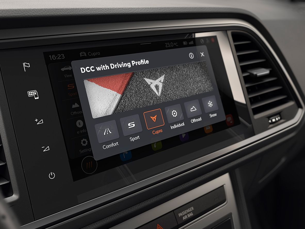 Palubná doska automobilu s integrovaným digitálnym displejom systému infotainment. Na displeji sú rôzne jazdné režimy vrátane športového a komfortného. Ovládacie prvky dotykovej obrazovky sú jasne viditeľné.