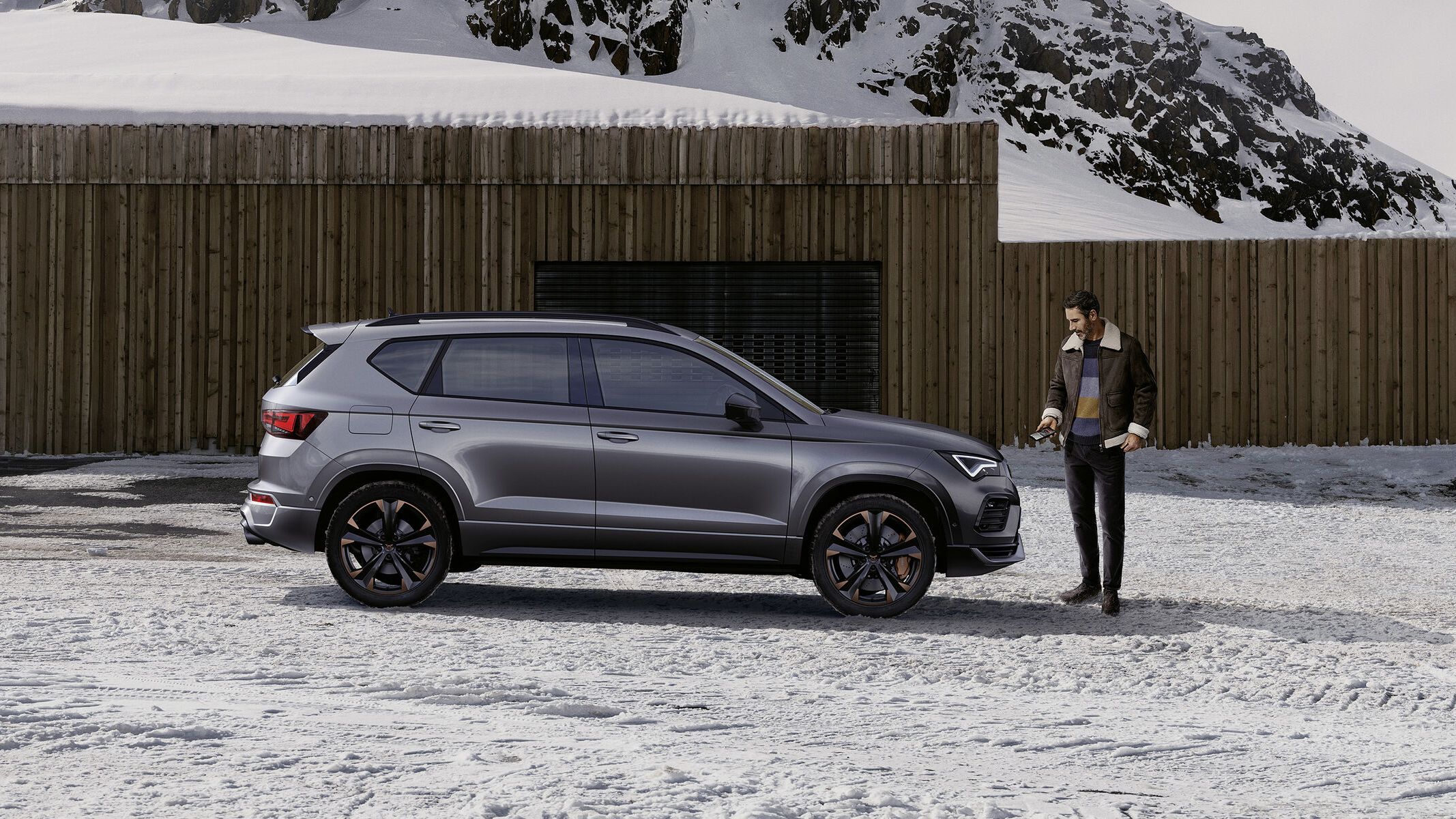 Ein CUPRA Ateca in grau, eine Frau steht davor