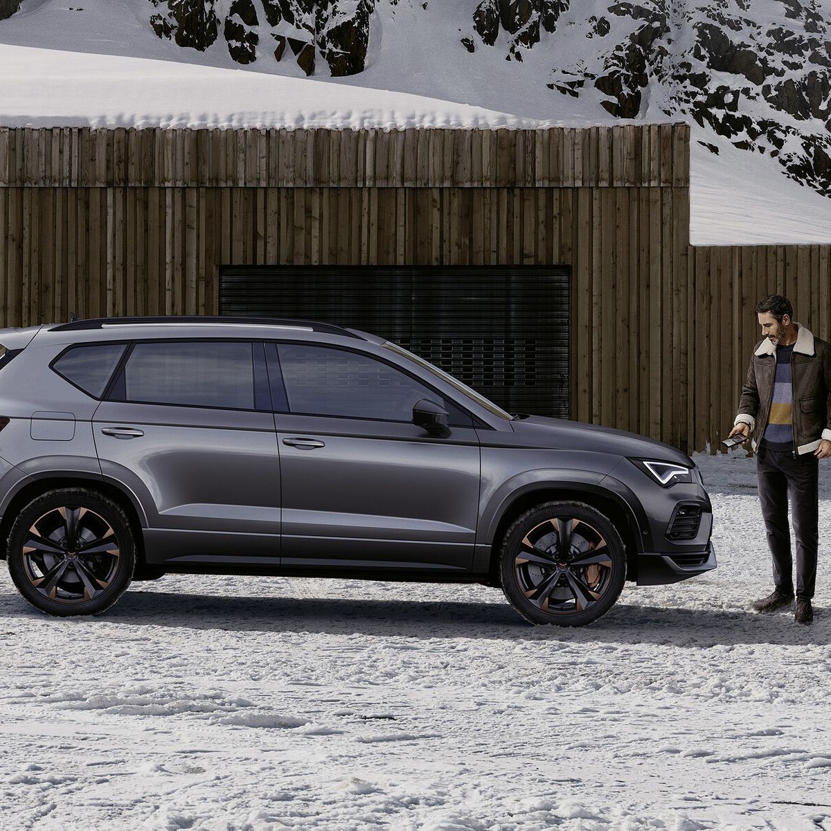 Ein CUPRA Ateca in grau, eine Frau steht davor